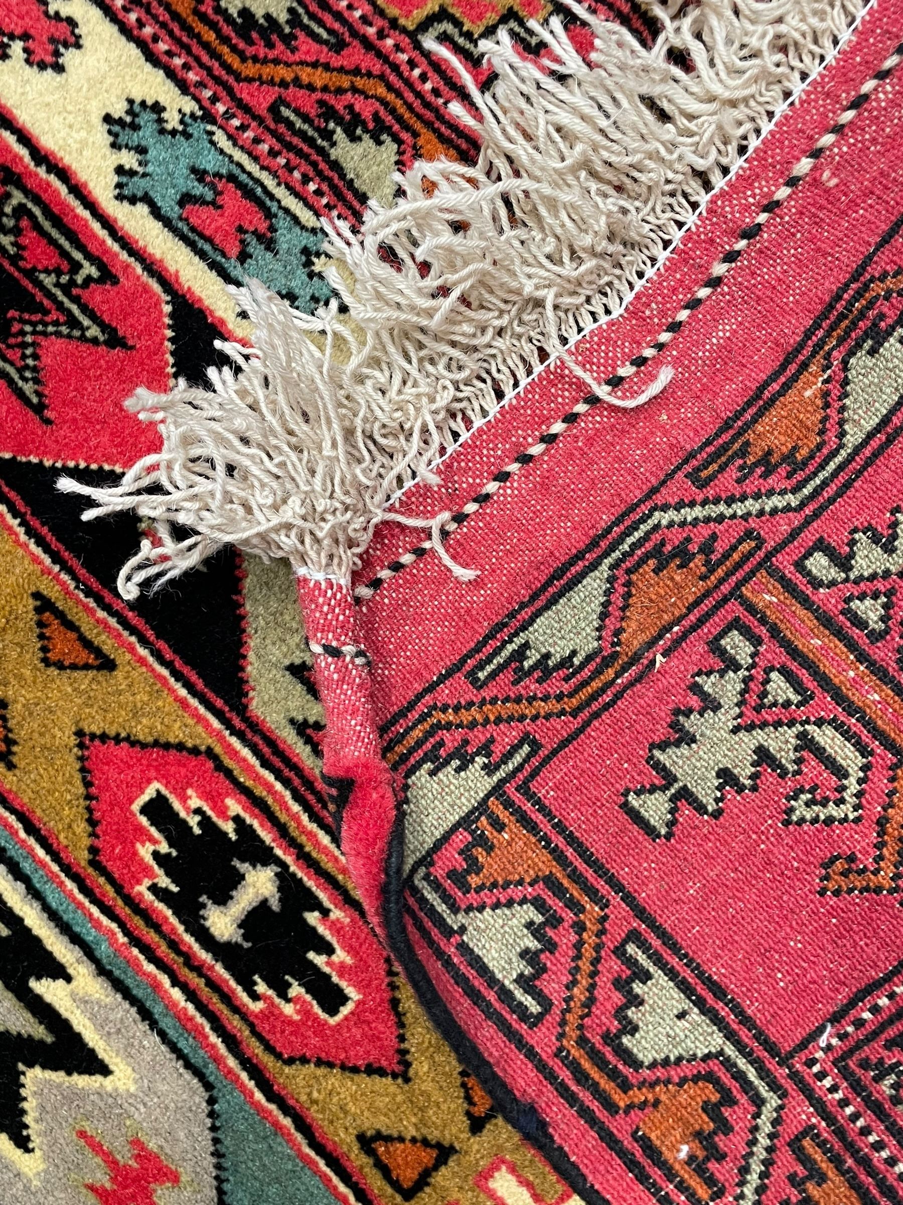 Turkaman red ground rug, the field divided into horizontal rows and decorated with geometric motifs, intricately pattern borders and end panels