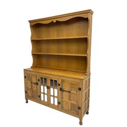 Yorkshire oak - adzed oak dresser, the rack with projecting cornice over shaped frieze and two shelves, the dresser fitted with central glazed double cupboard flanked by two panelled single cupboards, panelled sides