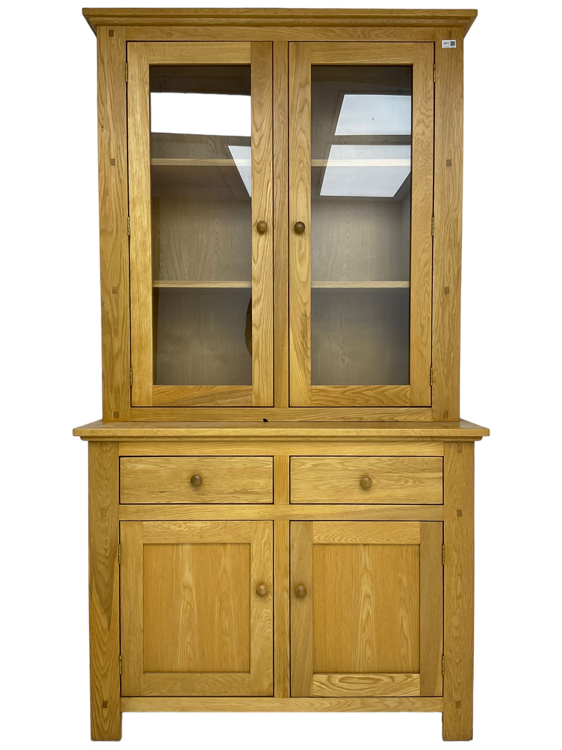 Contemporary light oak bookcase display cabinet, fitted with  two glazed doors enclosing two shelves, above two drawers and cupboards