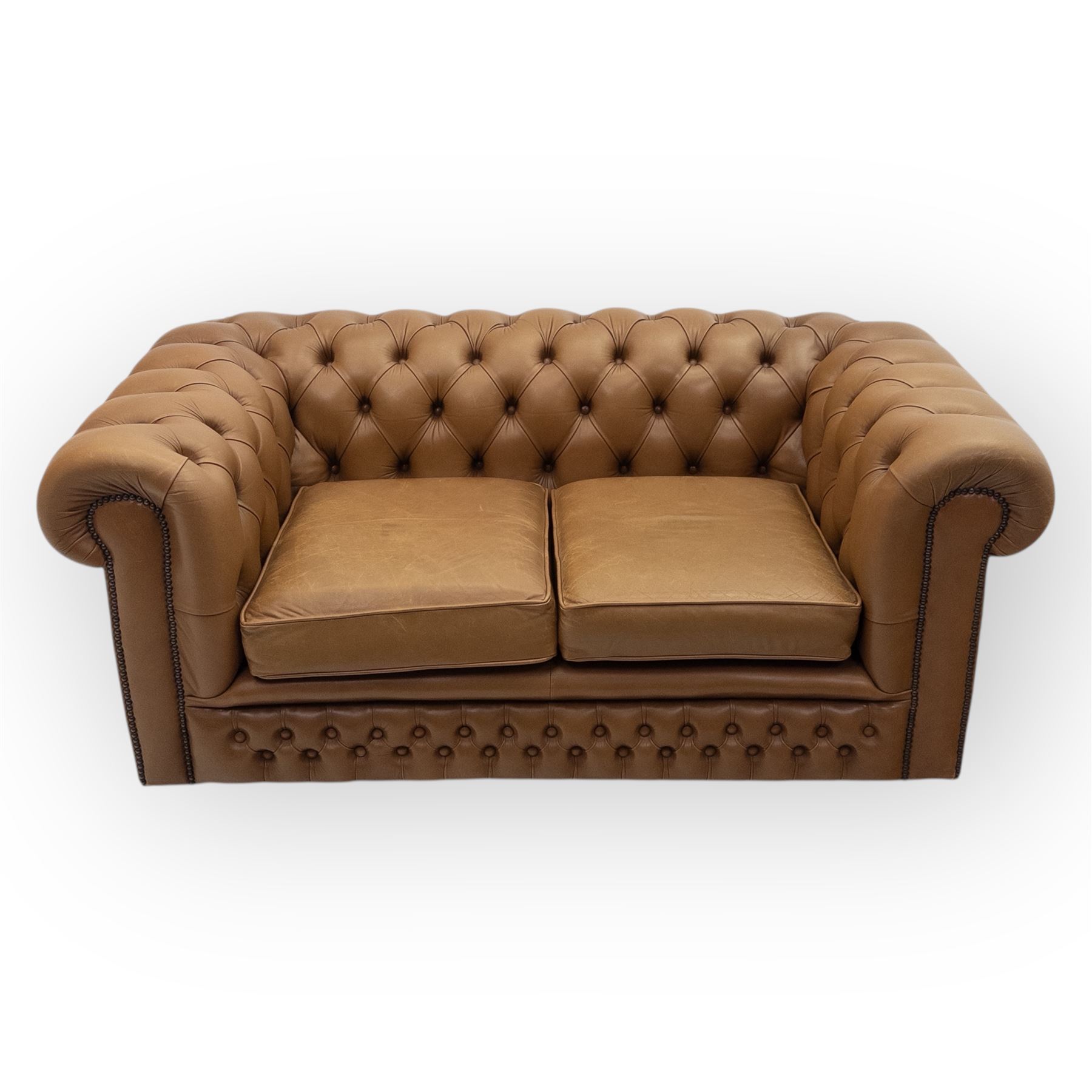 Contemporary tan leather chesterfield settee, deep button upholstered throughout with rolled arms and back of equal height, brass stud detailing, twin seat cushions