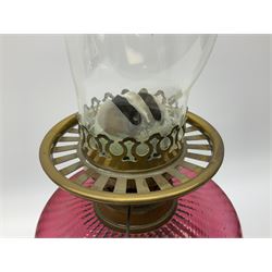 Victorian table standing oil lamp, brass fittings, cranberry glass reservoir, brass column on black enamelled ceramic base, with a frosted glass shade and clear glass chimney, H68cm