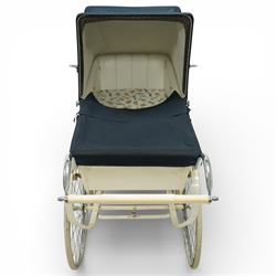 Mid-20th century Osnath pram, the cream painted metal body with navy fabric hood and apron, cream vinyl lined interior fitted with patterned mattress, raised on sprung metal supports with spoked wheels and white rubber tyres