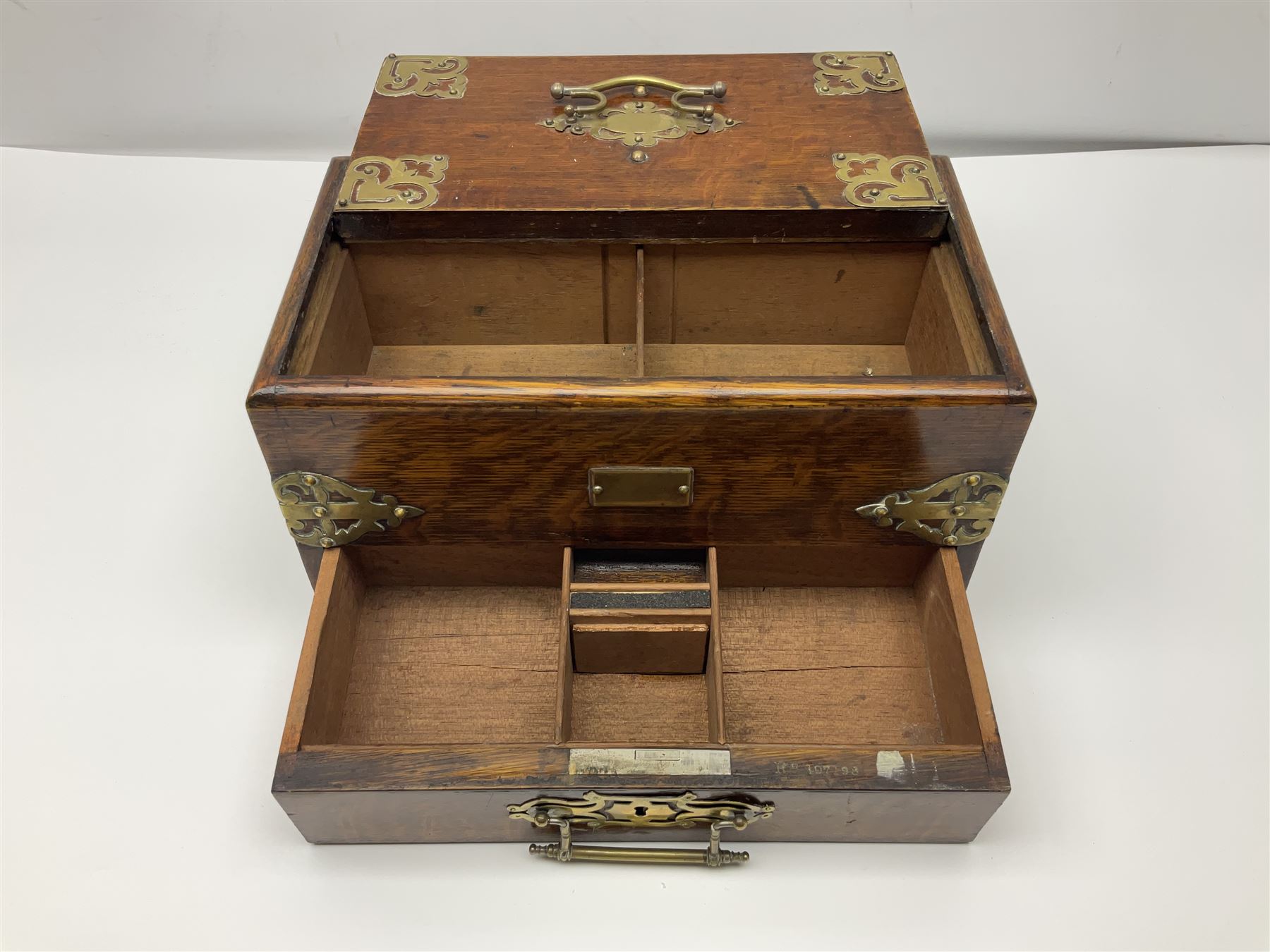Brass mounted oak humidor, the slide action top opening to a base drawer, cedar lined with central compartment and striker, the drawer stamped Rd 107198, H17cm, D18cm