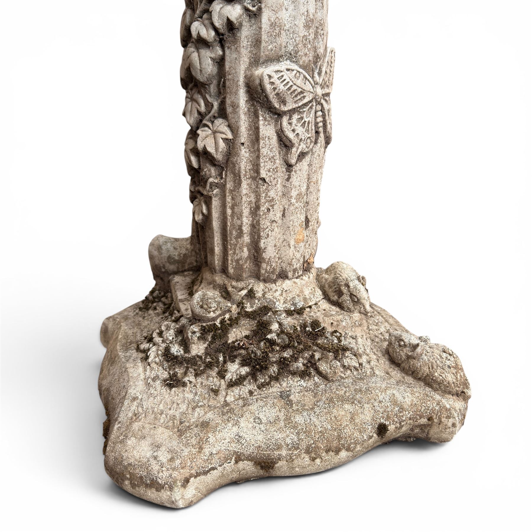 Pair of weathered composite stone garden figures, modelled as a girl and a young satyr playing the panpipes seated on column supports, the fluted columns with climbing ivy vines and surmounted animal, butterfly and other zoomorphic motifs