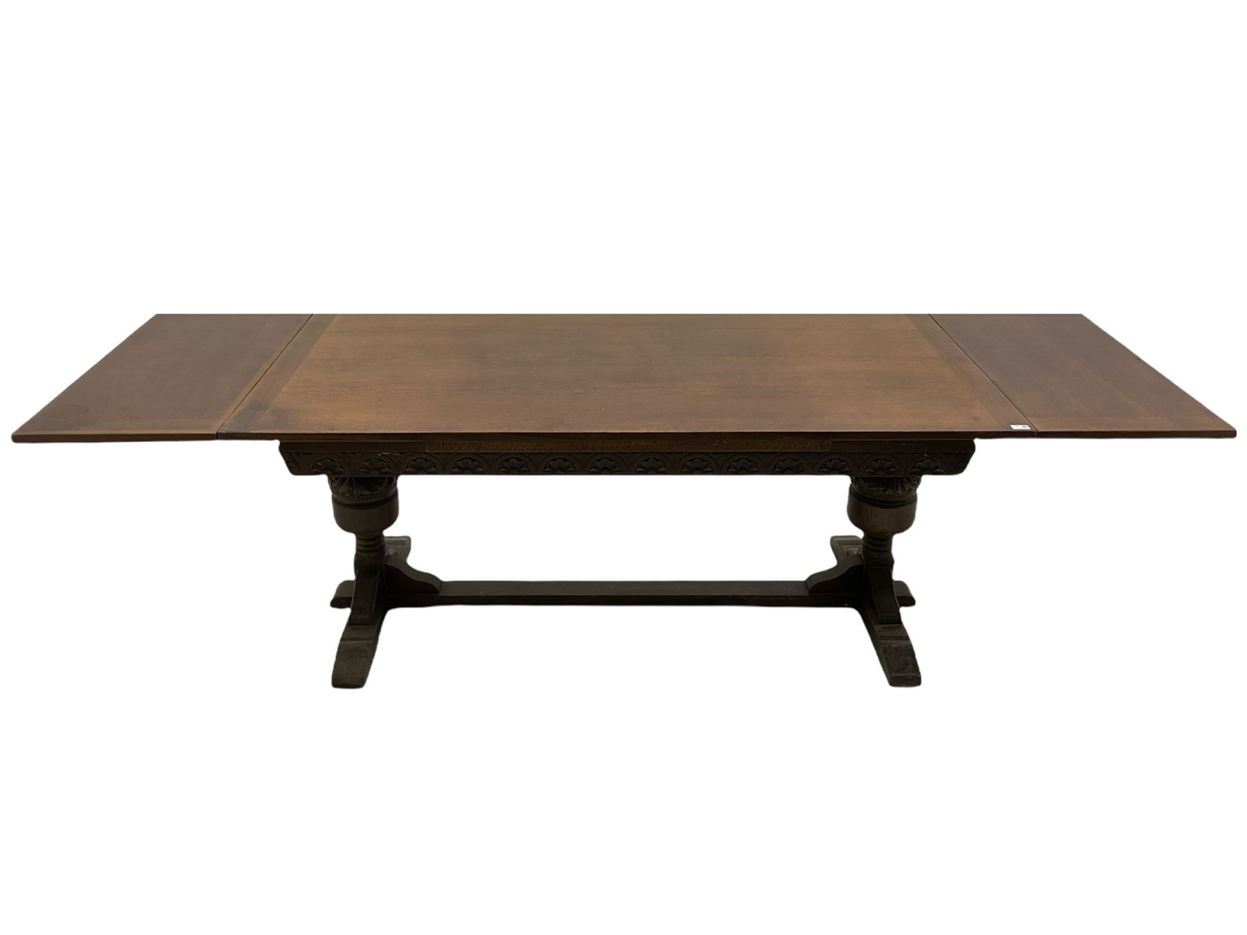 20th century oak drawer leaf extending dining table, two foliage carved baluster supports on sledge feet joined by floor stretcher 