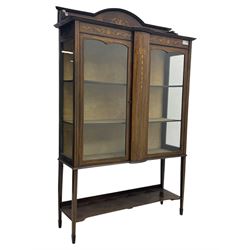 Edwardian mahogany and satinwood crossbanded display cabinet, arched pediment centred by marquetry scrollwork and ribbon decoration, twin glazed doors enclosing a lined a shelved interior, raised on square tapering supports joined by a shaped undertier with diamond parquetry inlay, terminating in spade feet