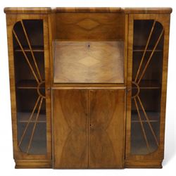 Art Deco walnut bureau bookcase, top with moulded and rounded edges and stepped front profile, central shelf, and fall-front bureau section with vertical and horizontal pigeon holes and a small drawer, above two cupboard doors and flanked by two tall glazed display cabinets with single doors and geometric sunburst design astragal glazing bars enclosing three shelves, raised on cavetto shaped plinth base 
