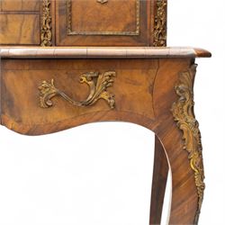 Late 19th-century Louis XV revival gilt bronze mounted and walnut Bonheur-de-Jour, rectangular-shaped serpentine form, with gilt bronze beading, frieze with two blind drawers and gilt bronze handles, centre drawer with large central serves style porcelain plaque, the elevated section with brass gallery above panelled cupboard doors also with serves style porcelain plaques and gilt bronze mounts, interior with single shelf, central section with four drawers each with gilt bronze handles, raised on slender cabriole legs fitted with gilt bronze rococo style masks and sabots