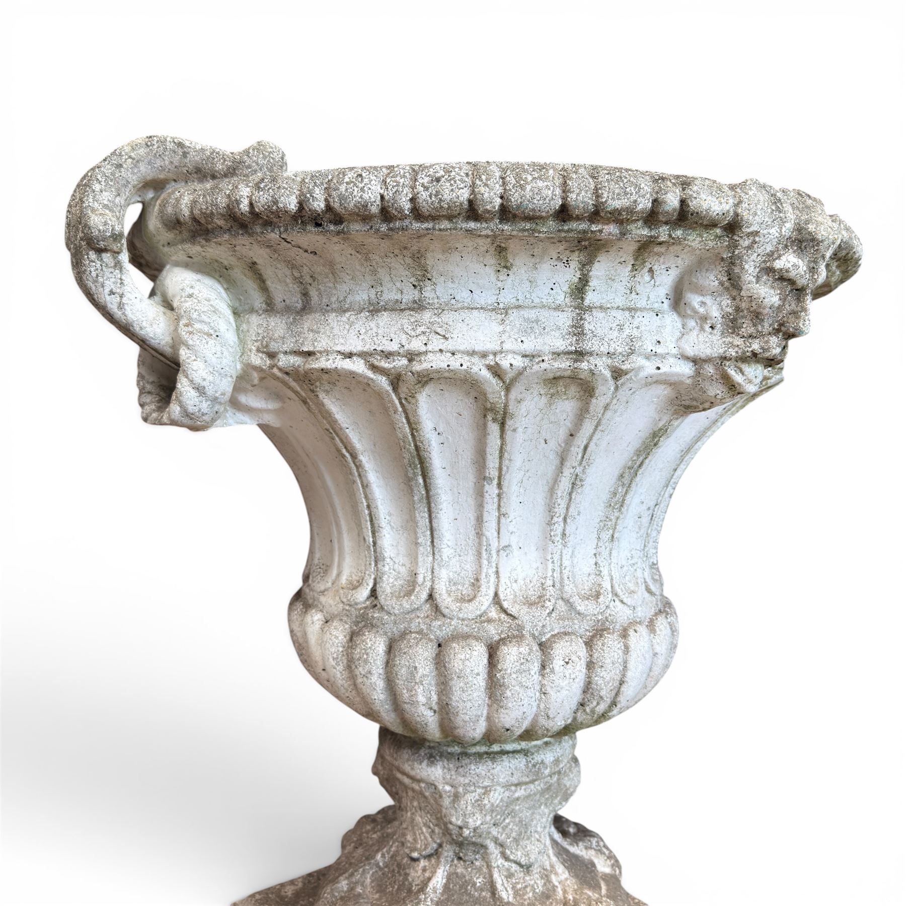 Pair of Neoclassical design cast stone garden urns, each of campana form with fluted body and gadrooned underbelly, decorated with faun/satyr opposing masks and ropetwist handles, with floral and mask design to the socles, raised on square bases, finished in weathered white patina