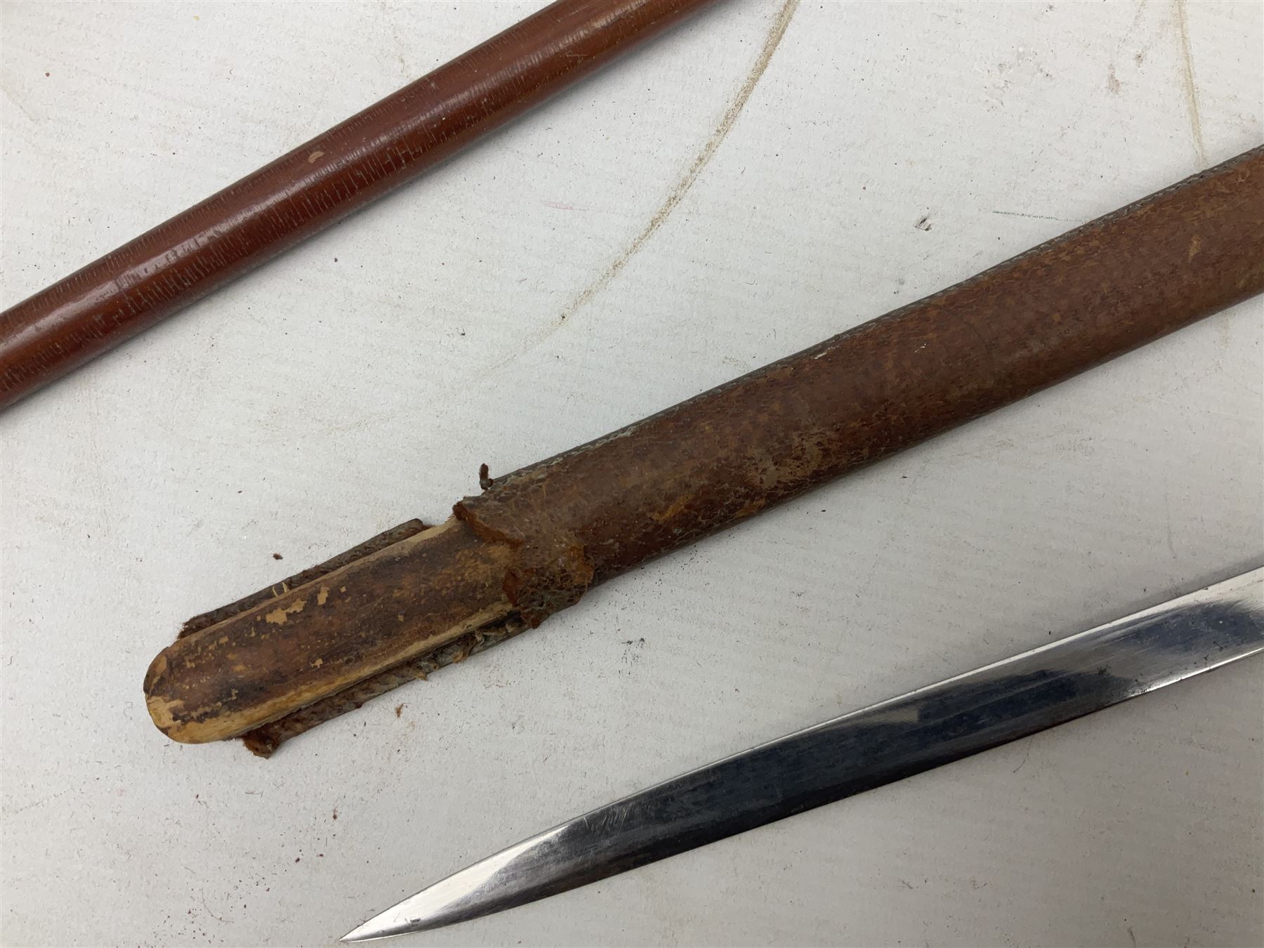 George V 1897 pattern Army Officer's sword by Henry Wilkinson Pall Mall London, the 82.5cm 'London Made' blade etched to both sides with Royal Crests and cyphers etc, pierced half-basket hilt with wire-bound fish skin grip and remains of leather knot strap; in leather covered field service scabbard L101cm overall; and two 14th Prince of Wales Own swagger sticks (3)