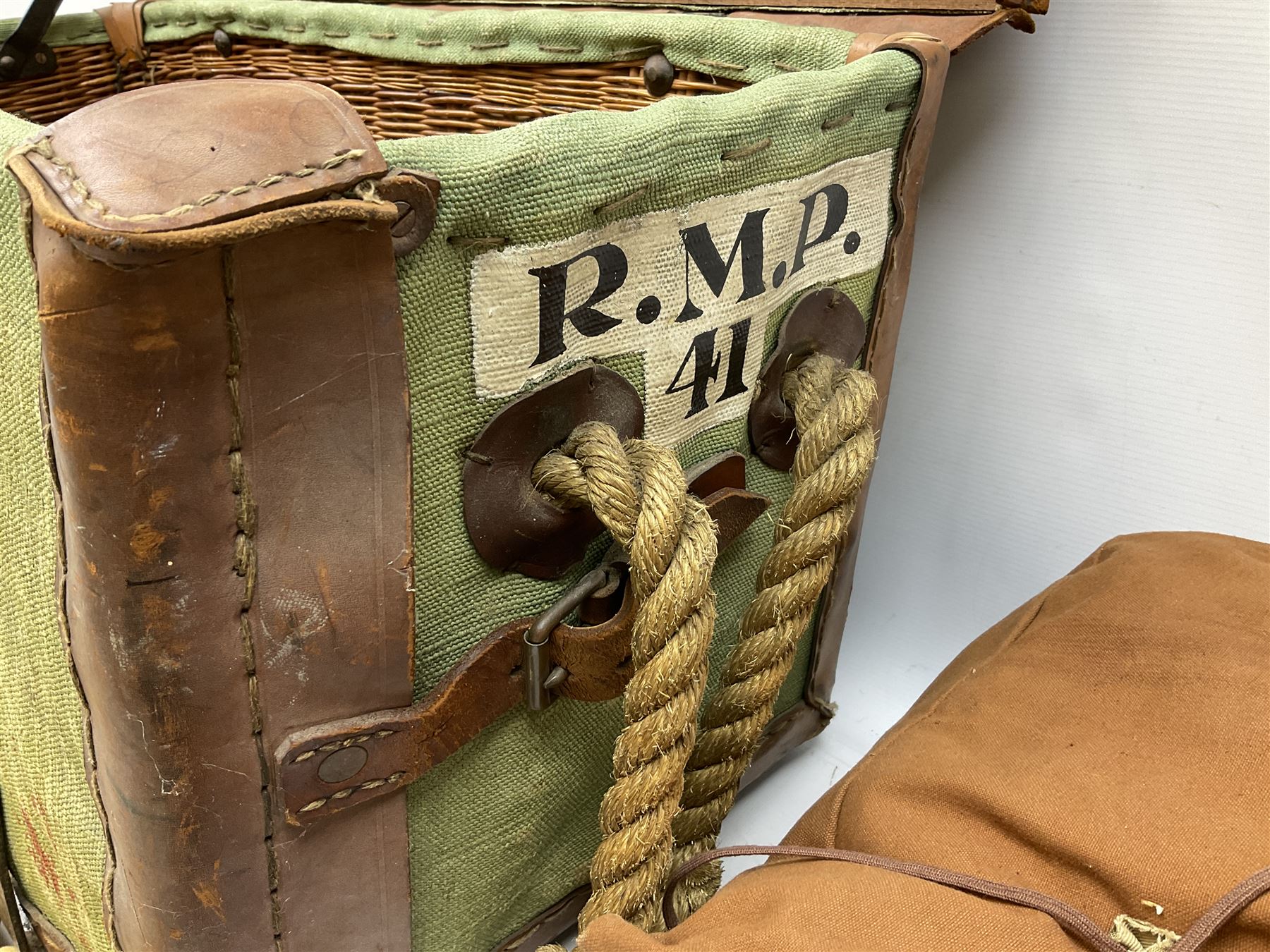 WW2 British Army RAMC 'Regimental Medical Pannier', well marked externally and dated 1941, stamped May 1943 internally, canvas covered wicker form with leather edges, hinged top and fall front with two rope carrying handles, fitted iron locking straps with securing chains; contains various unused field dressings and bandages with WW2 dates and two pillows; original label under lid L79cm
