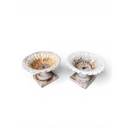 Coalbrookdale - pair of 19th century cast iron petal rim urns, squat form on square plinth, finished in distressed white paint, design registration number 133334, first registered 19 september 1860, number 19 in the Coalbrookdale Castings Catalogue (see illustration)
