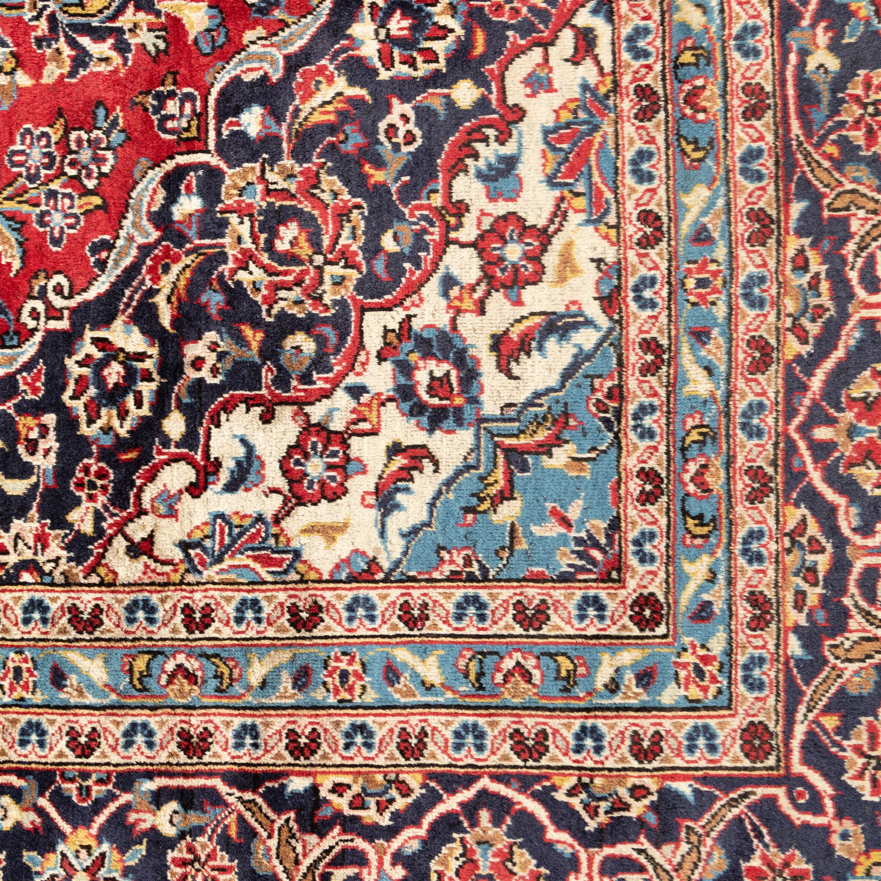Persian Ardakan carpet, brick red field with ivory and navy central medallion, surrounded by stylised lotus blossoms and cloudband motifs, framed by rich indigo borders featuring palmettes, serrated leaves and angular vine work, woven in the city of Ardakan in central Iran
