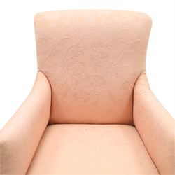 Edwardian mahogany framed armchair of traditional shape, high sprung back and seat over squared padded arms, upholstered in foliate patterned pale pink upholstery, on square tapering supports with brass castors