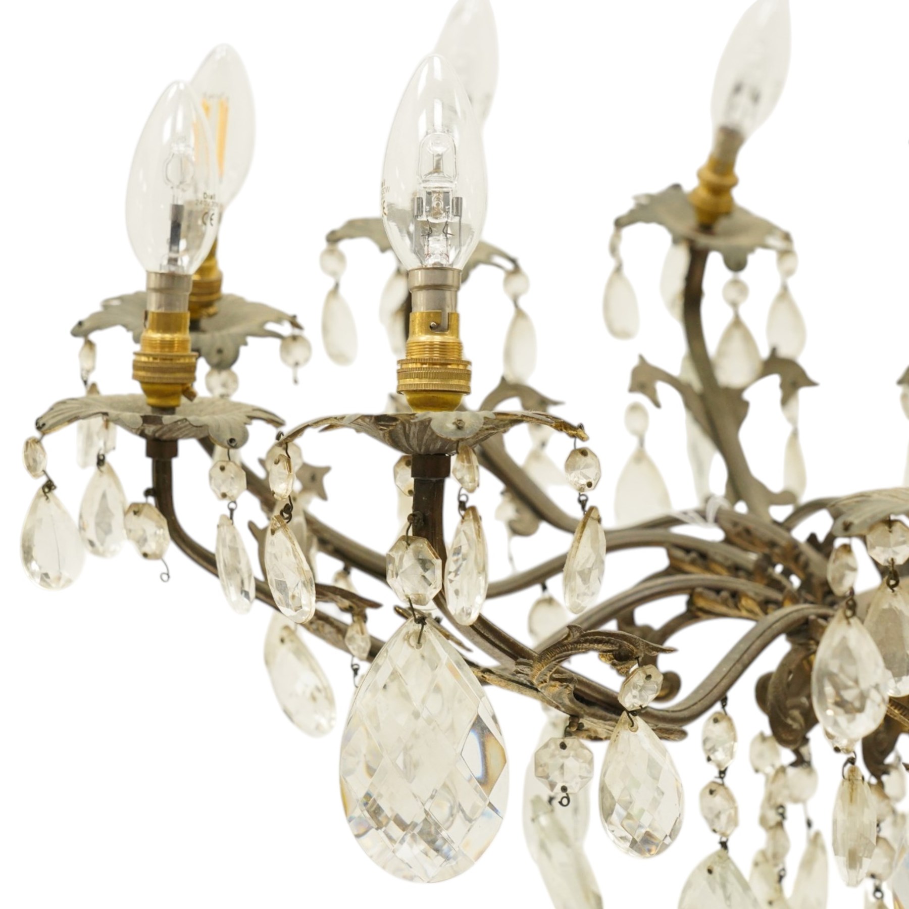 20th century Louis XV design gilt and patinated metal twelve-light chandelier, the foliate-cast baluster stem issuing scrolling acanthus branches with leaf-form drip pans, hung throughout with faceted glass pendants and lustre drops, suspended from chains beneath a foliate ceiling rose