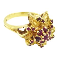 18ct gold ruby flower head cluster ring, seven round cut rubies surrounded by textured leaves, each spaced by two rubies, stamped 750