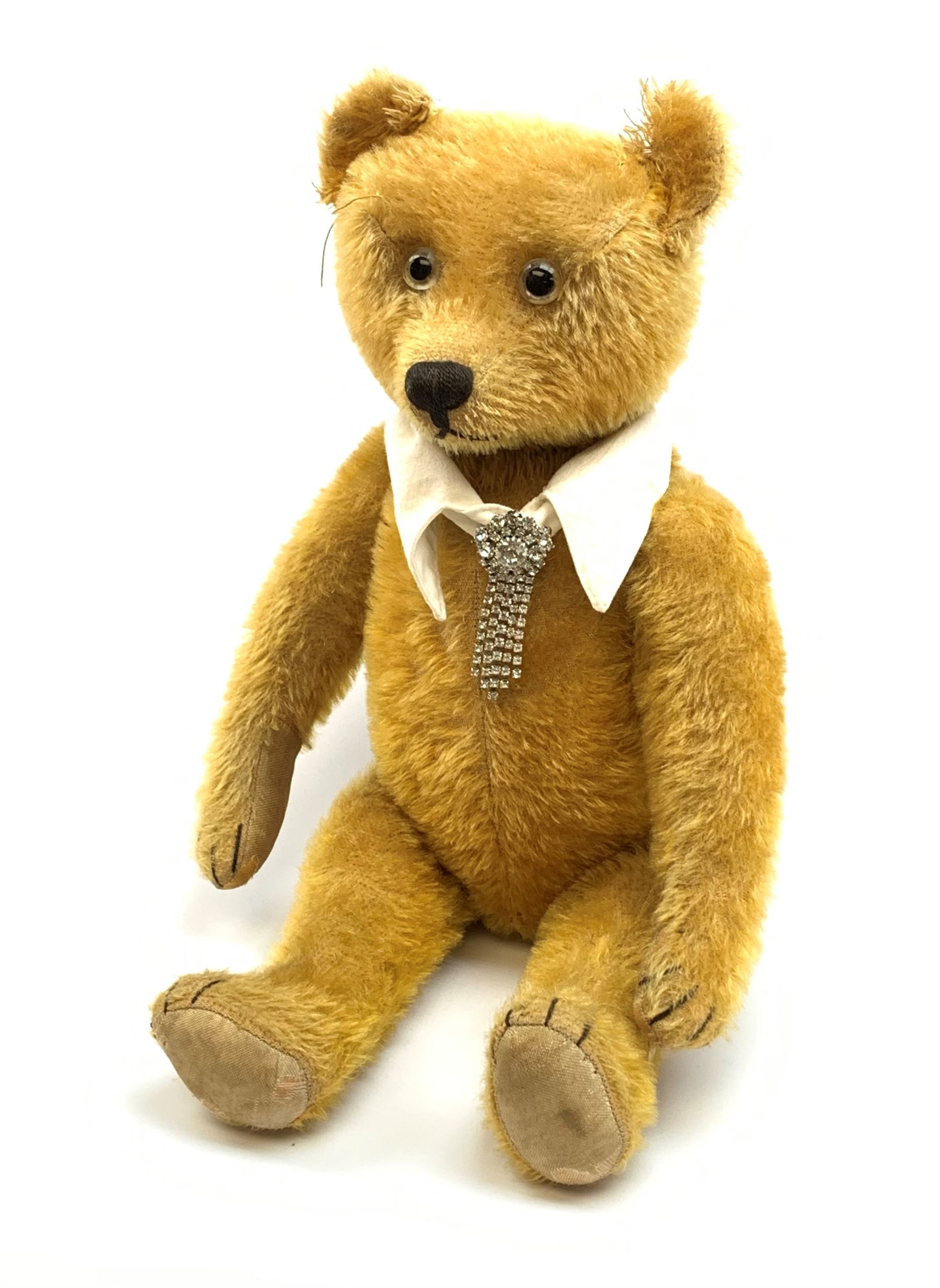 Schuco 'yes-no' teddy bear c1925 with wood wool filled short golden mohair body, linen pads with stitched claws and  tail-operated moving head with glass eyes and vertically stitched nose and mouth H18