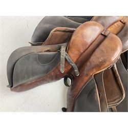 Collection of nine saddles, mainly havana leather to include a racing saddle and a Goodwin saddle, some with stirrups and leathers 