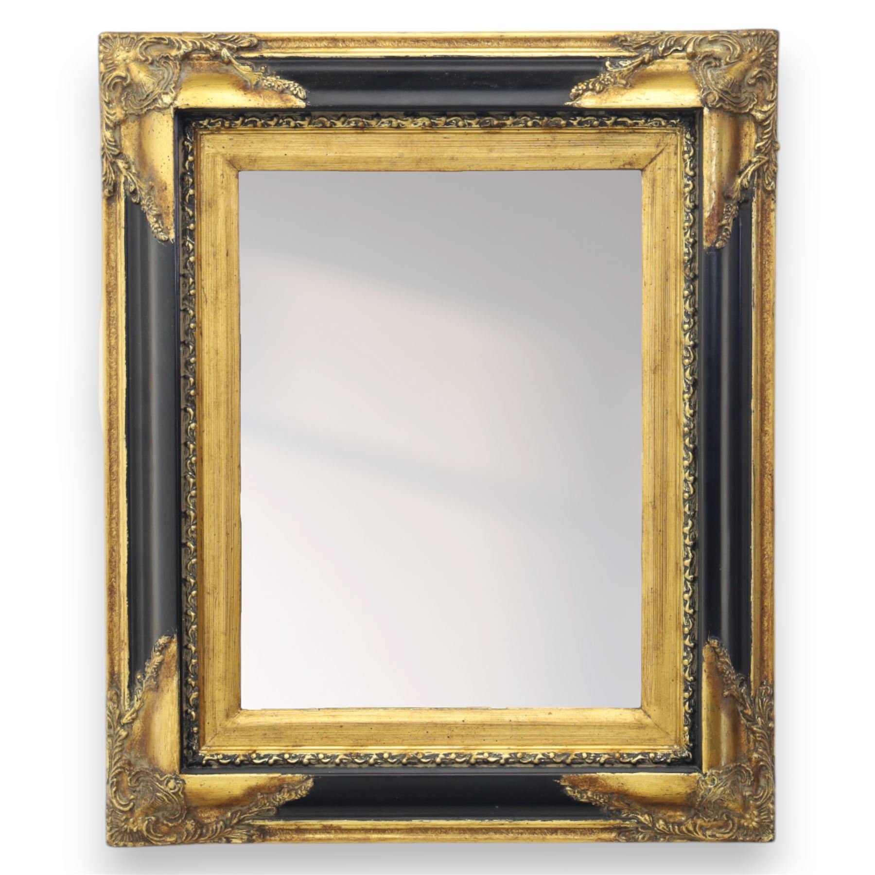 19th century design rectangular wall mirror, set within a swept giltwood and gesso frame, with foliate corner mounts and ebonised inner border, enclosing a bevelled mirror plate
