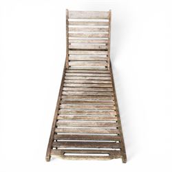 Pair of teak garden sun loungers, with slatted adjustable backrests, integrated wheels and sliding pull-out side trays, weathered natural finish.