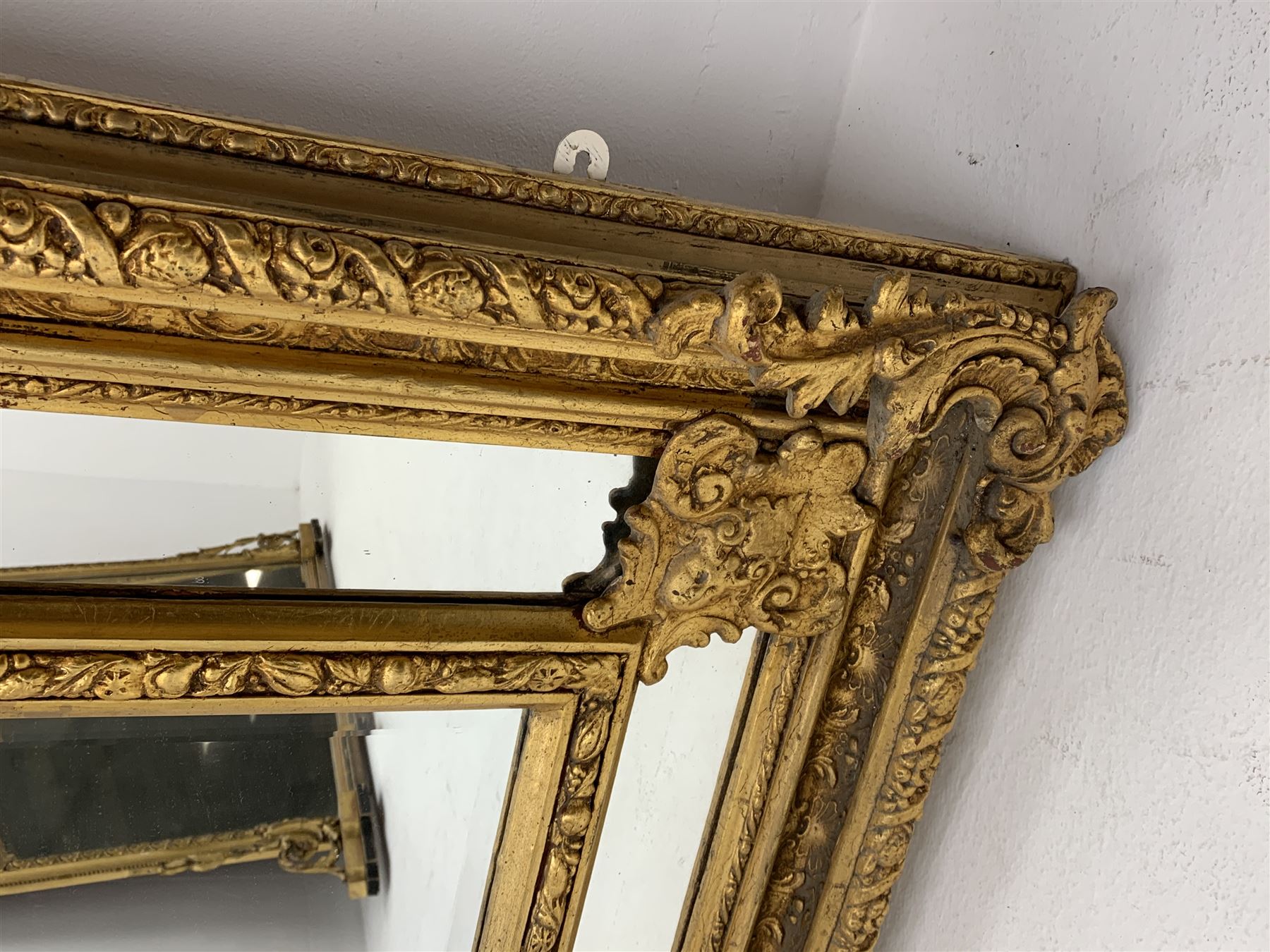 Gilt Rococo style mirror, arched top with central cartouche and oak leaf moulded pediment, floral and fruit moulded surround with segmented glass panels, bevelled central pane, c-scroll shell and acanthus leaf brackets