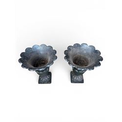 Pair of Victorian large scale cast iron garden urns, flared petal shaped rim with tapering waist, gadrooned base on square plinth, finished in black paint