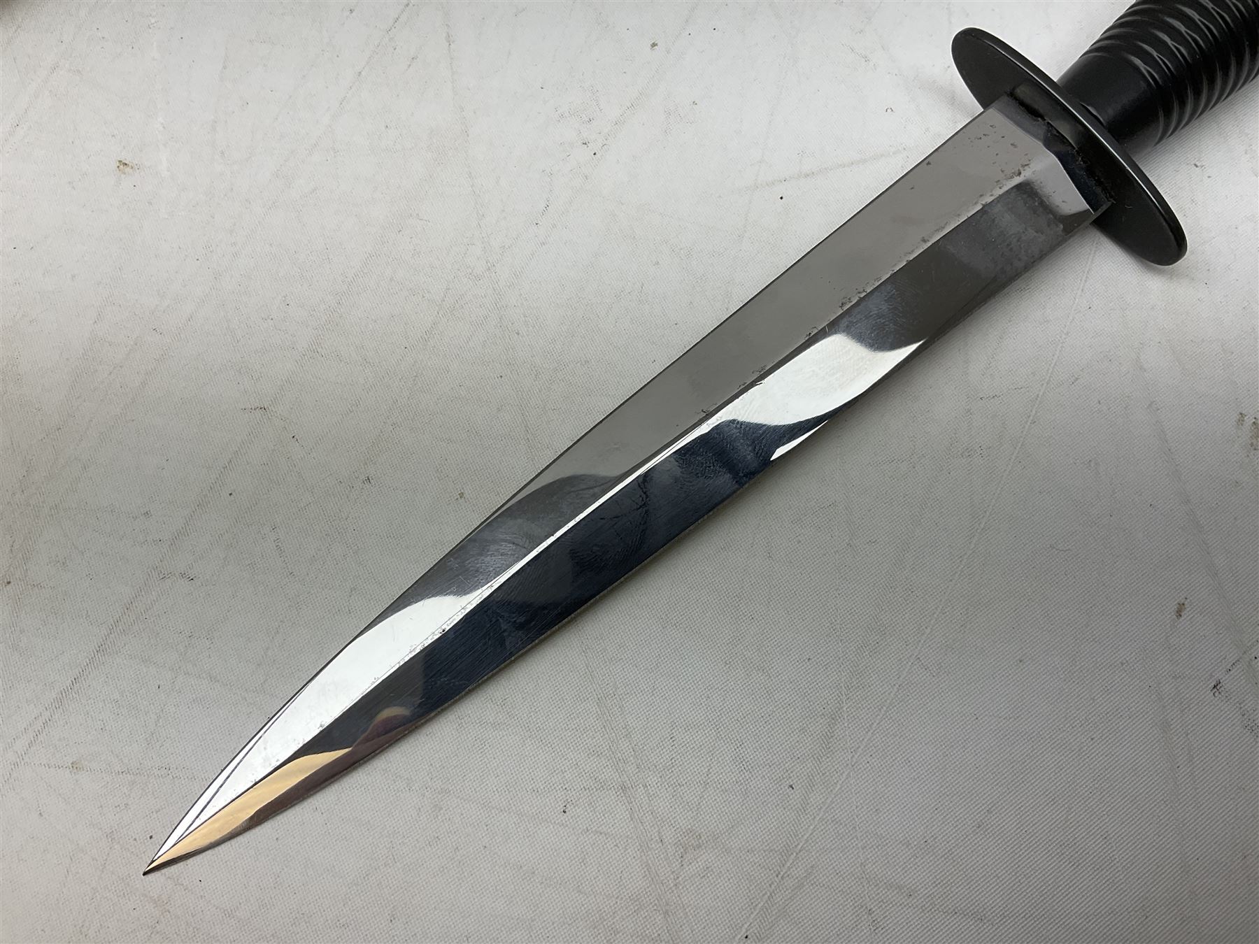 Gulf War period commando knife with 17cm double-edged steel blade etched with the crest and motto 'By Strength and Guile', blackened cross-piece and grip; in webbing scabbard L31cm overall