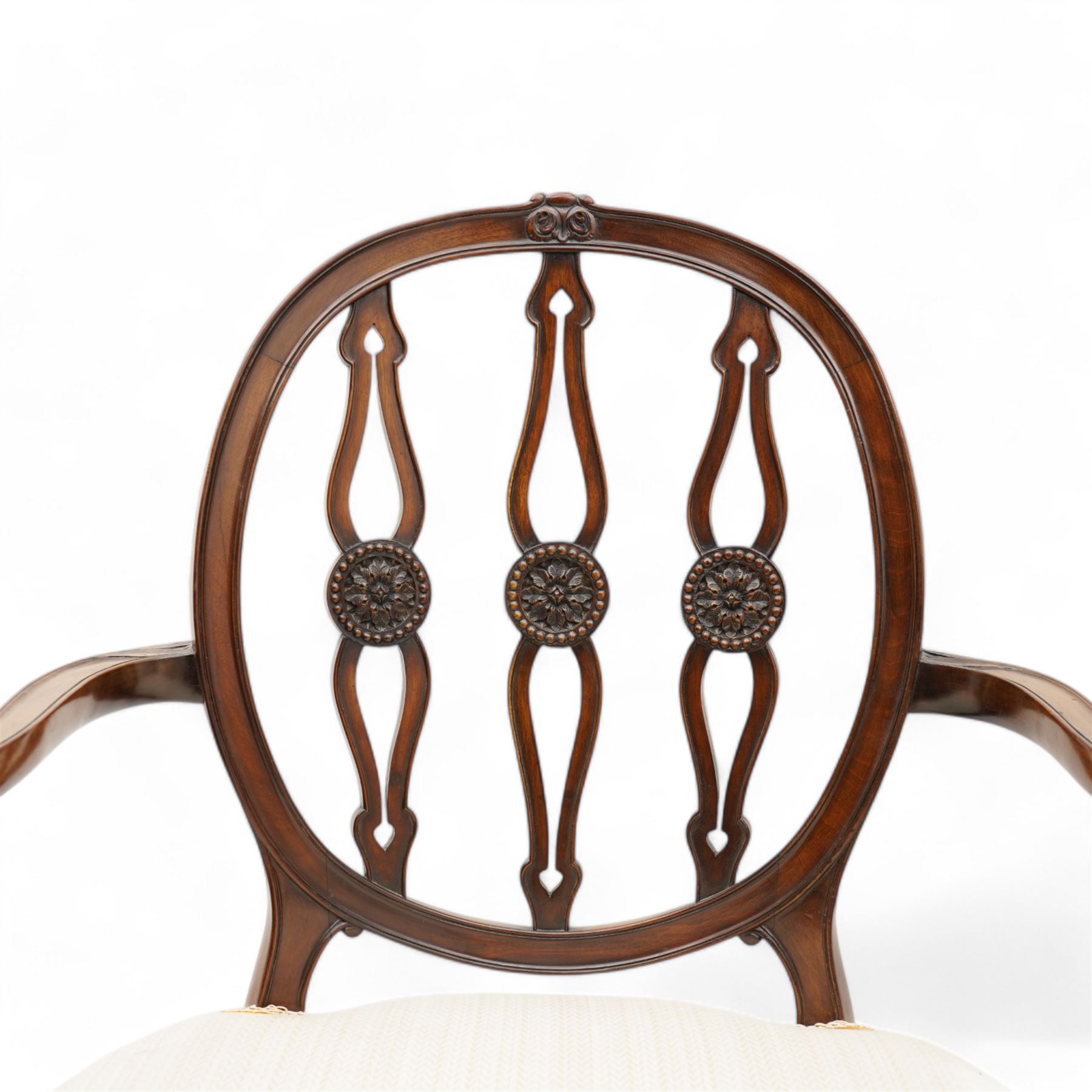 Set of six (4+2) late 19th to early 20th century Hepplewhite design mahogany dining chairs, moulded oval framed back with three shaped and pierced upright rails decorated with floral carved roundels, upholstered in pale fabric, on square tapering supports with recessed panels and block feet 