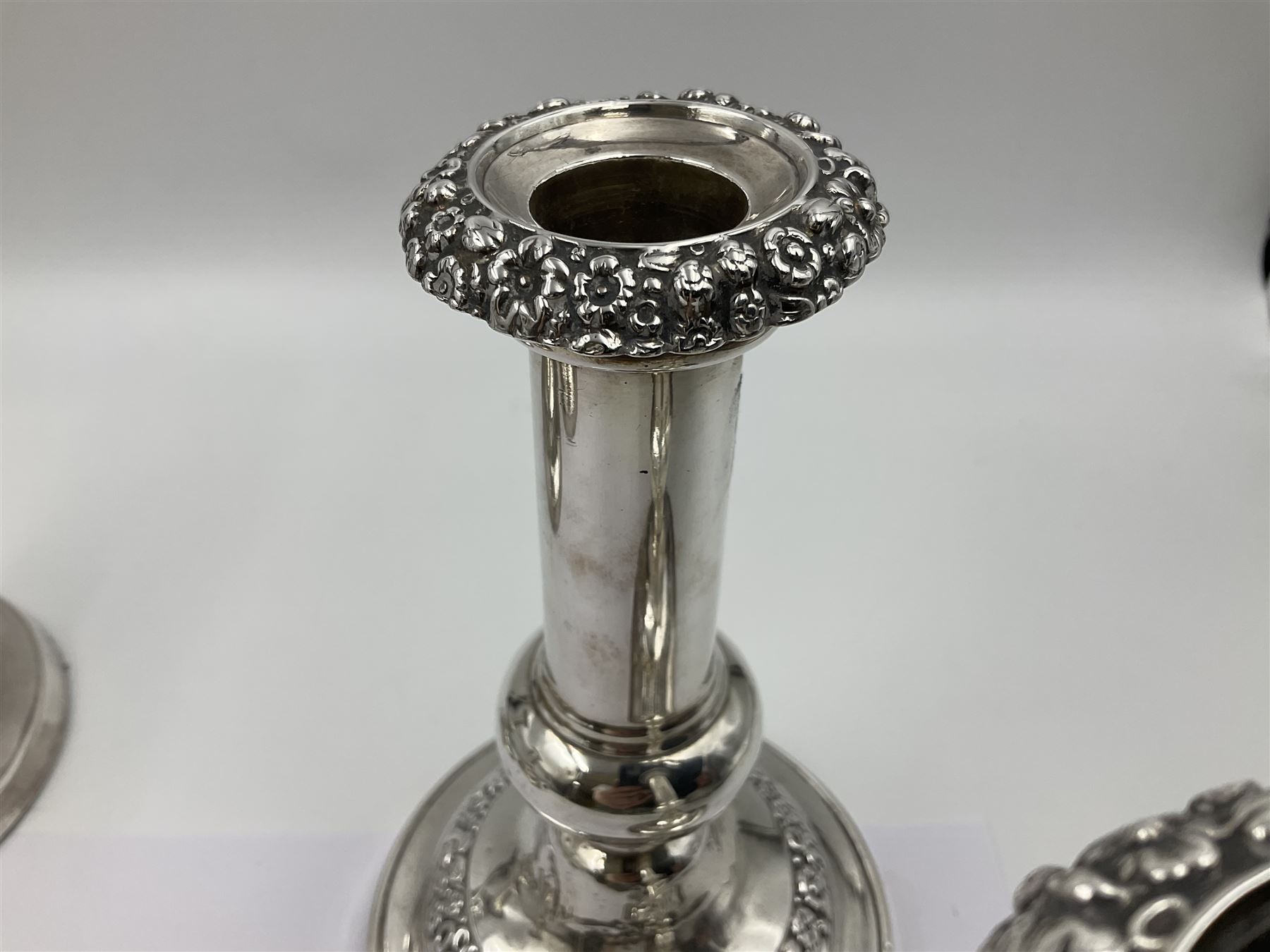 Four George III silver candlesticks, each upon knopped stem and weighted circular stepped foot, the foot and removable sconce repousse decorated with a band of flower heads, hallmarked to sconce and foot Thomas & John Settle, Sheffield 1820, H17.5cm