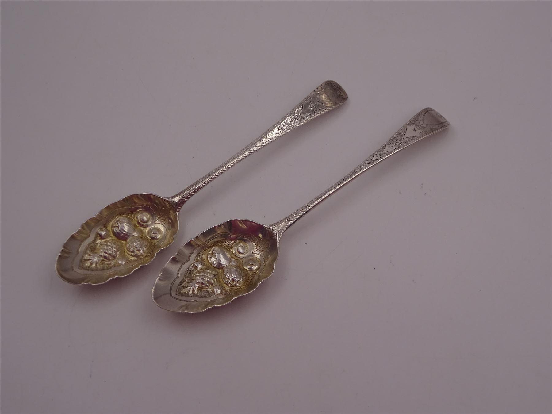 George IV silver fruit serving spoon, the bowl embossed with fruits, with engraved vine leaf decoration to handle, hallmarked London 1789, together with a very similar earlier example, hallmarks worn and indistinct