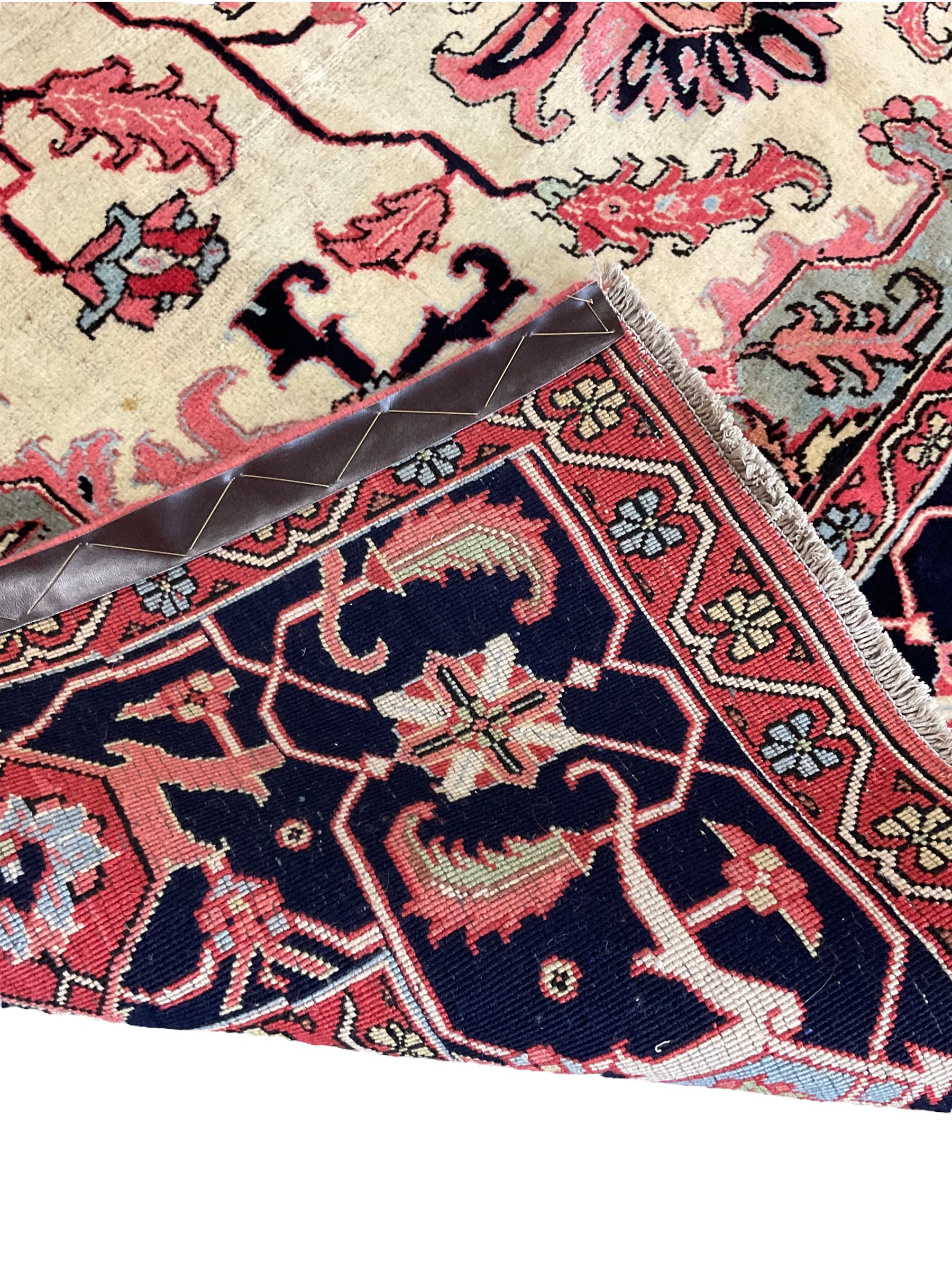 North West Persian Heriz carpet, ivory ground with large central medallion and floral spandrels, triple band border with scrolling design decorated with flower head and plant motifs 