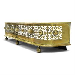 Victorian pierced brass fire fender, the pierced scrolling gallery of Aesthetic taste with applied roundels and protruding lobed mounts, raised on bun feet
