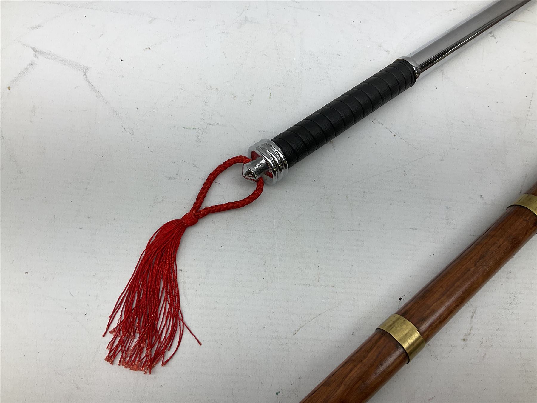 Two replica weapons, consisting of a double headed battle axe and a sword, together with a brass birdhead topped walking stick, stick H67cm