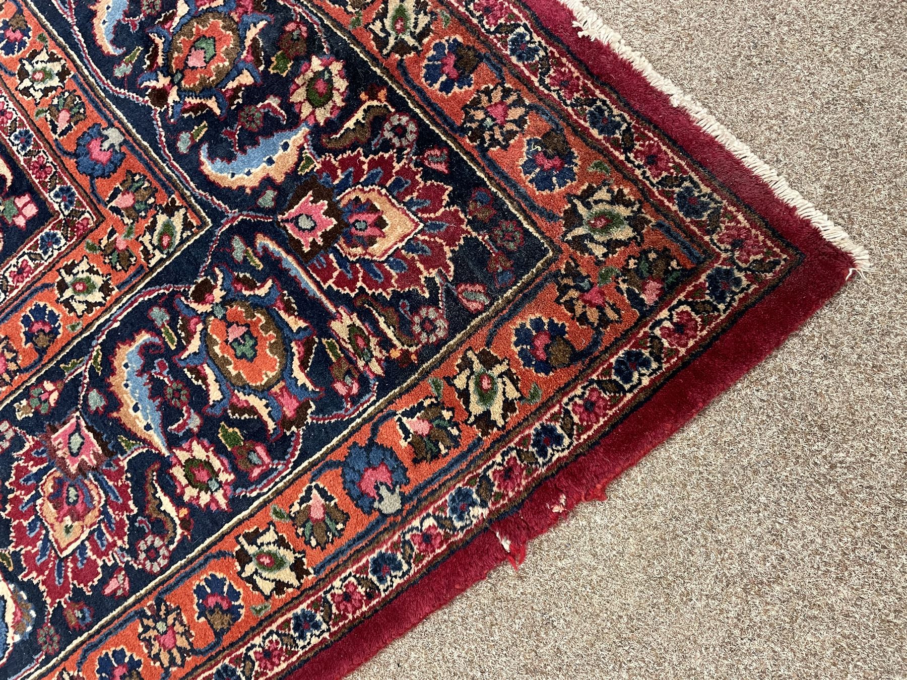 Persian Meshed carpet, plum ground and decorated with stylised flower heads and interlacing foliate, large central stylised medallion with orange detail, the orange mirrored in the five band border decorated with scrolling floral design, signature panel to end 
