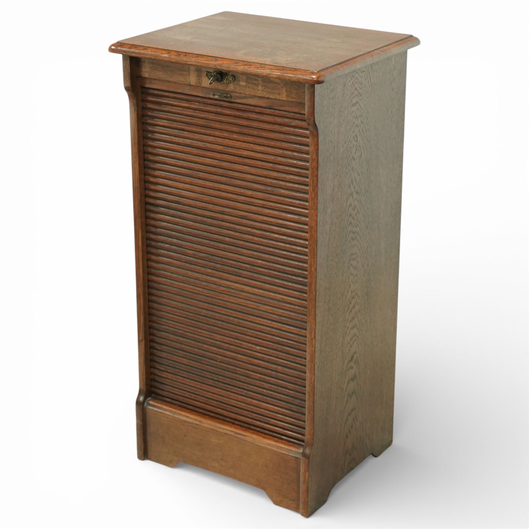 Early 20th century oak filing cabinet, the rectangular top with moulded edge above a tambour shutter enclosing a fitted interior with eleven shaped filing shelves, the sides with shaped uprights, raised on a plinth base