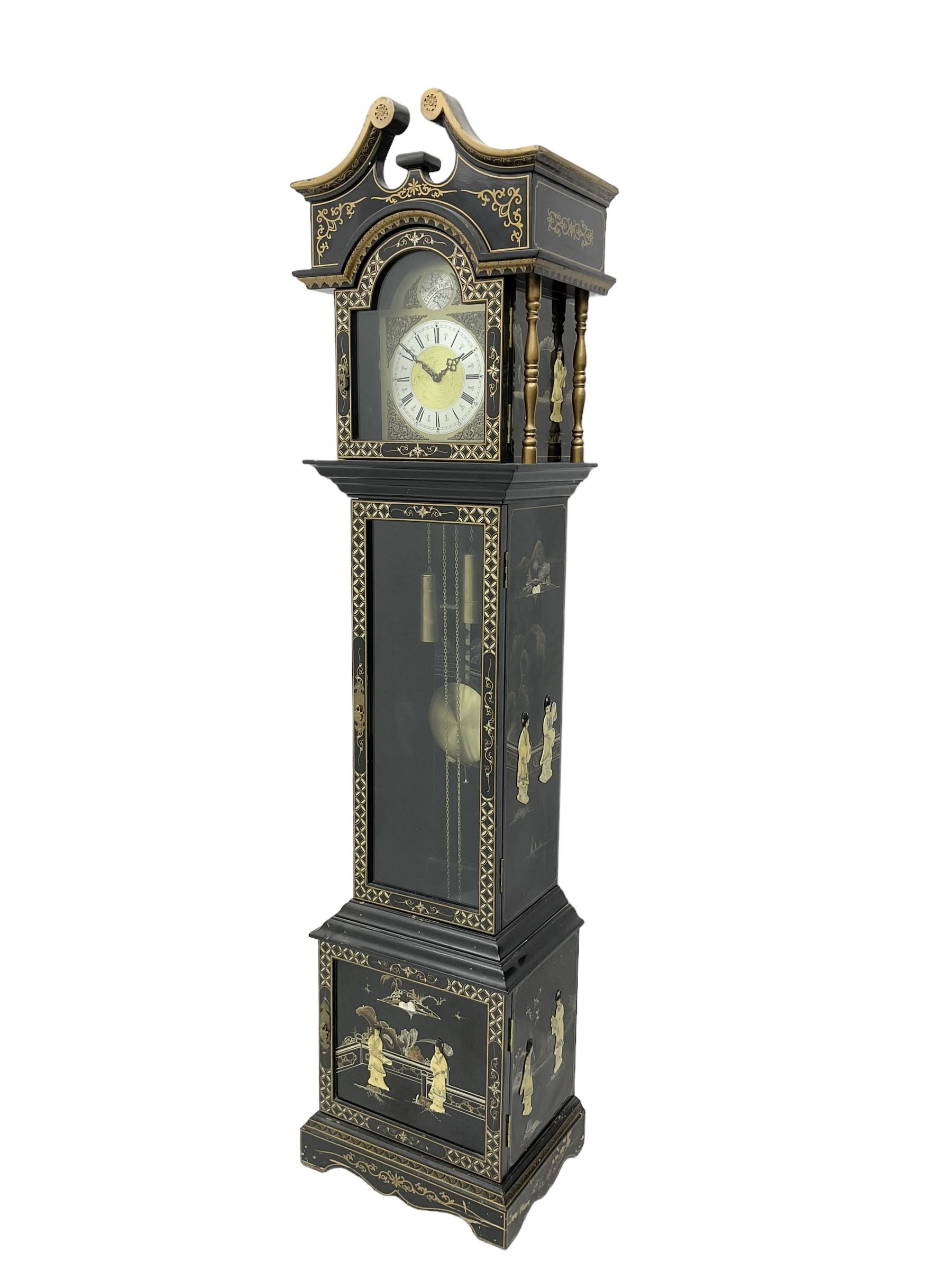 20th century 8-day chain driven black lacquered longcase clock - with a swans neck pediment and break-arch hood door, fully glazed trunk door displaying brass cased weights and pendulum, case sides, hood and plinth profusely decorated in gold relief and chinoiserie figures, brass break arch dial with an etched centre and silvered chapter ring, German two train movement striking the hours and half hours on two gong rods. With weights and pendulum.
