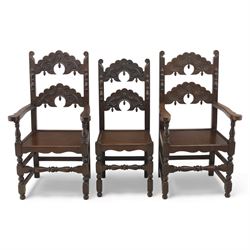 Early 20th century set of seven Jacobean Revival oak chairs, comprising pair of cavers and five chairs, each with carved mask and scroll decoration to the crest and and back rail, plain oak seat, upon turned front legs and block rear legs with conforming stretchers