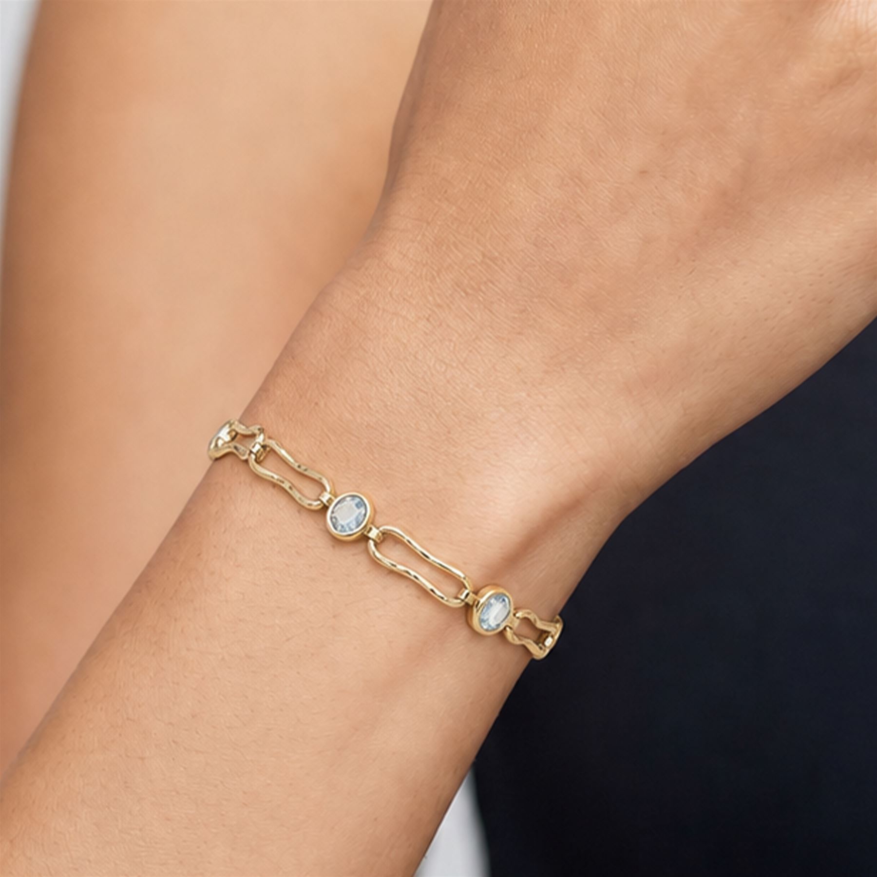 Gold blue topaz bracelet, bezel set with five oval cut topaz's, each spaced by fancy rectangular links, stamped 9ct