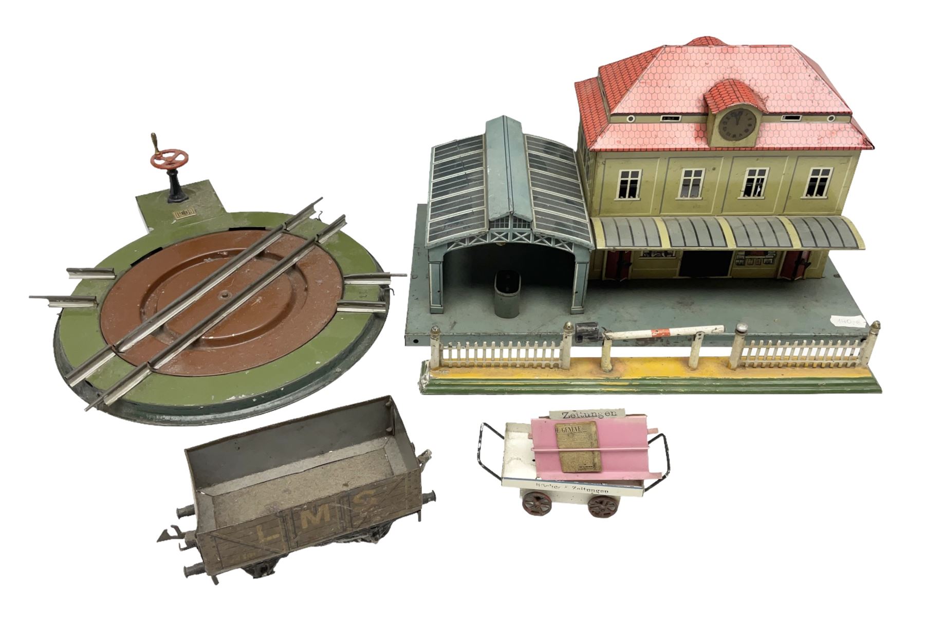 '0' gauge - Bing tin-plate two-storey double sided station with open walk-through to one end, rail side canopy, hinged doors and removable roof giving access to clock illumination L35cm; Bing hand-cranked turntable and open wagon; Marklin tin-plate level crossing barrier and Newspaper vendor's tin-plate four-wheel hand cart (5)