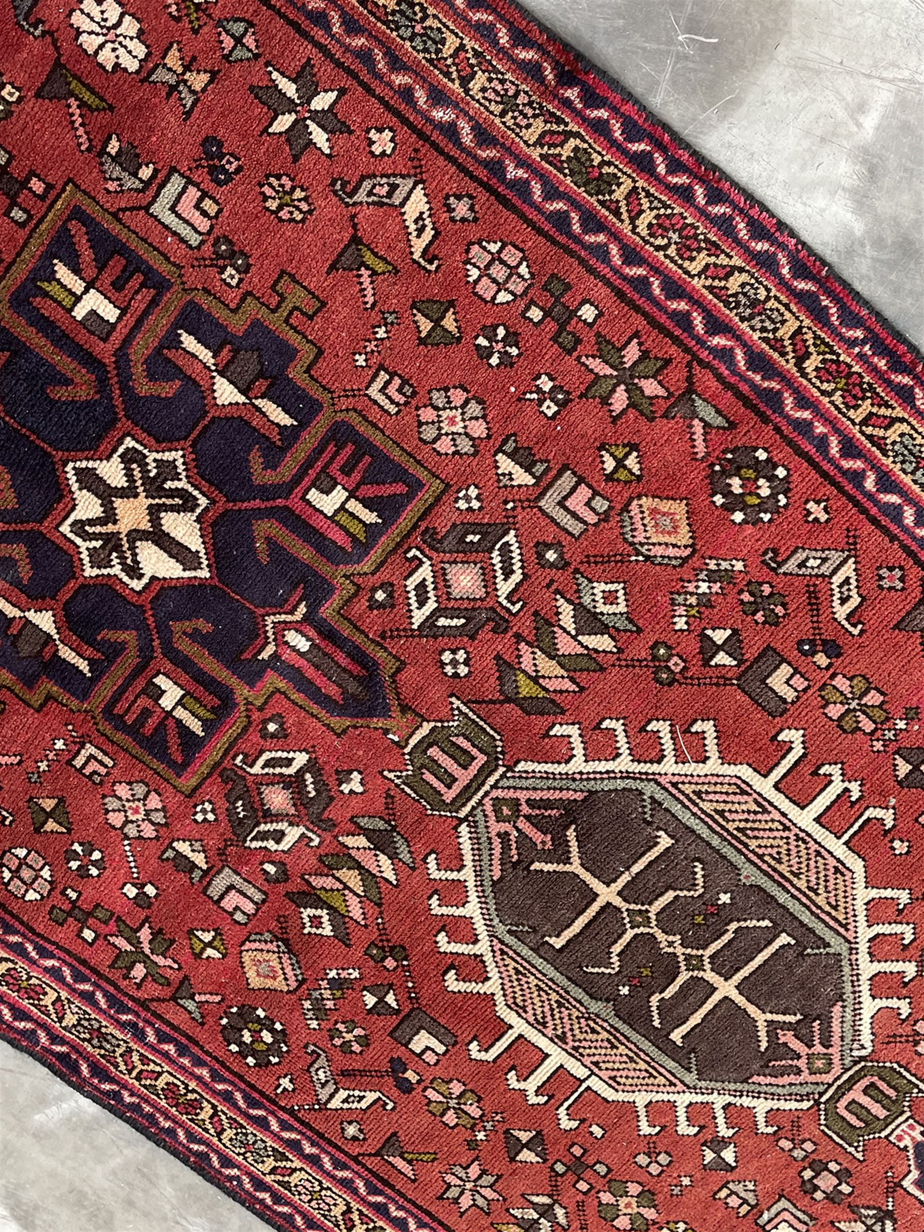 Persian Karajeh red ground runner, decorated with multiple stylised medallions and motifs