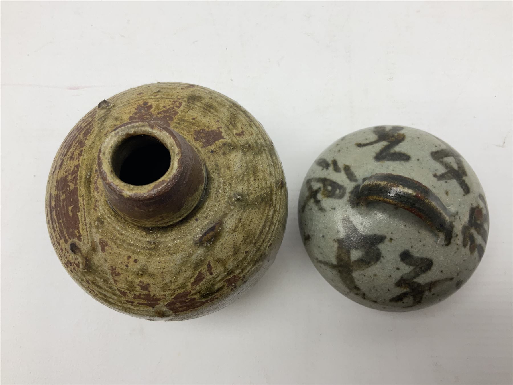 Janet Leach (American, 1918-1997) for Leach Pottery; speckled studio pottery vase of shouldered ovoid form with speckled brown decoration and trailing green and brown glaze upon beige and brown ground, with impressed J.L. monogram and Leach Pottery mark beneath, together with a Jeremy Leach blue speckled lidded circular dish with loop handle, impressed J.L, tallest H11cm