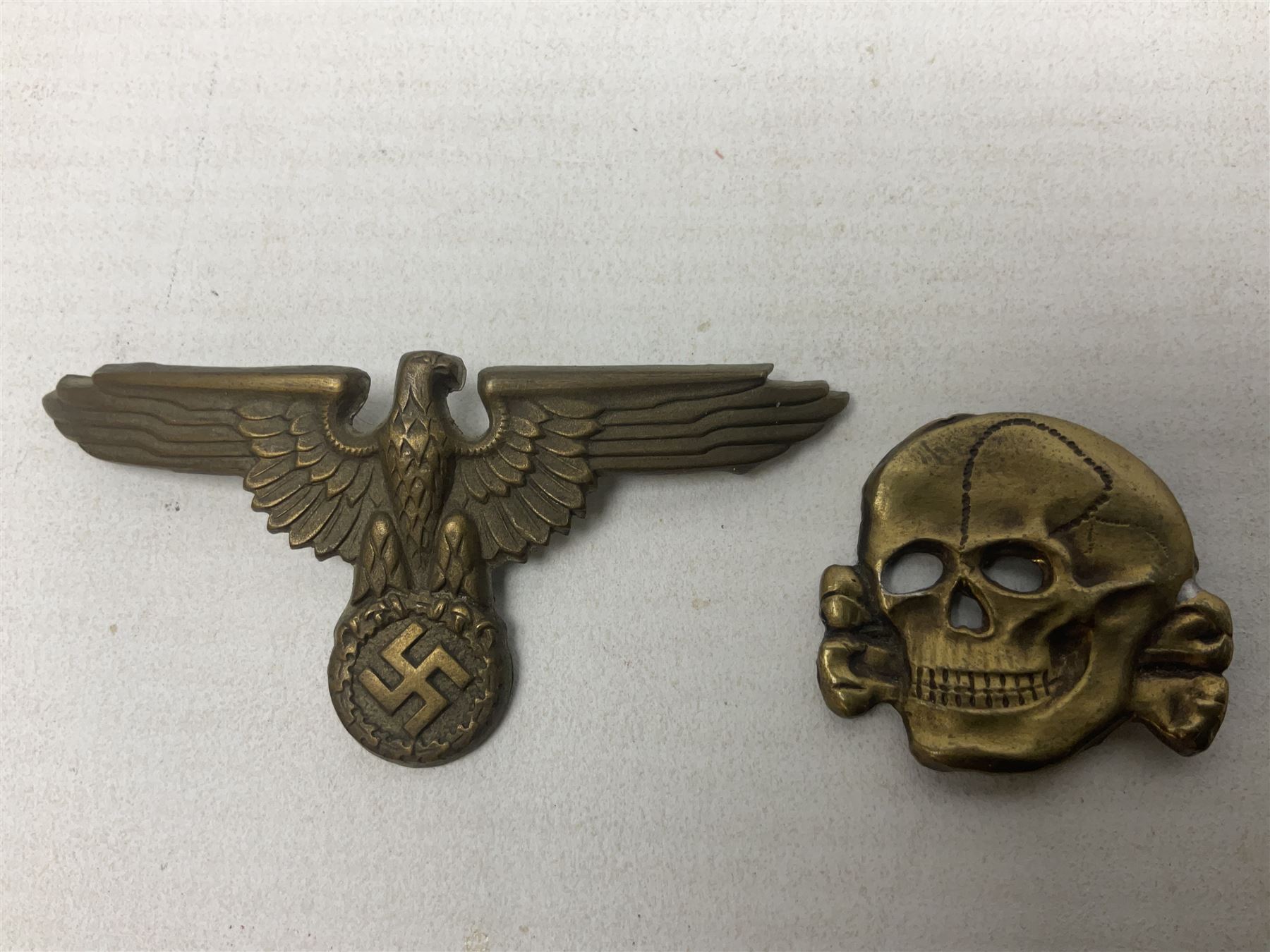 Two WW2 German 'SS' visor cap skull badges and another later; and visor cap eagle insignia (4)