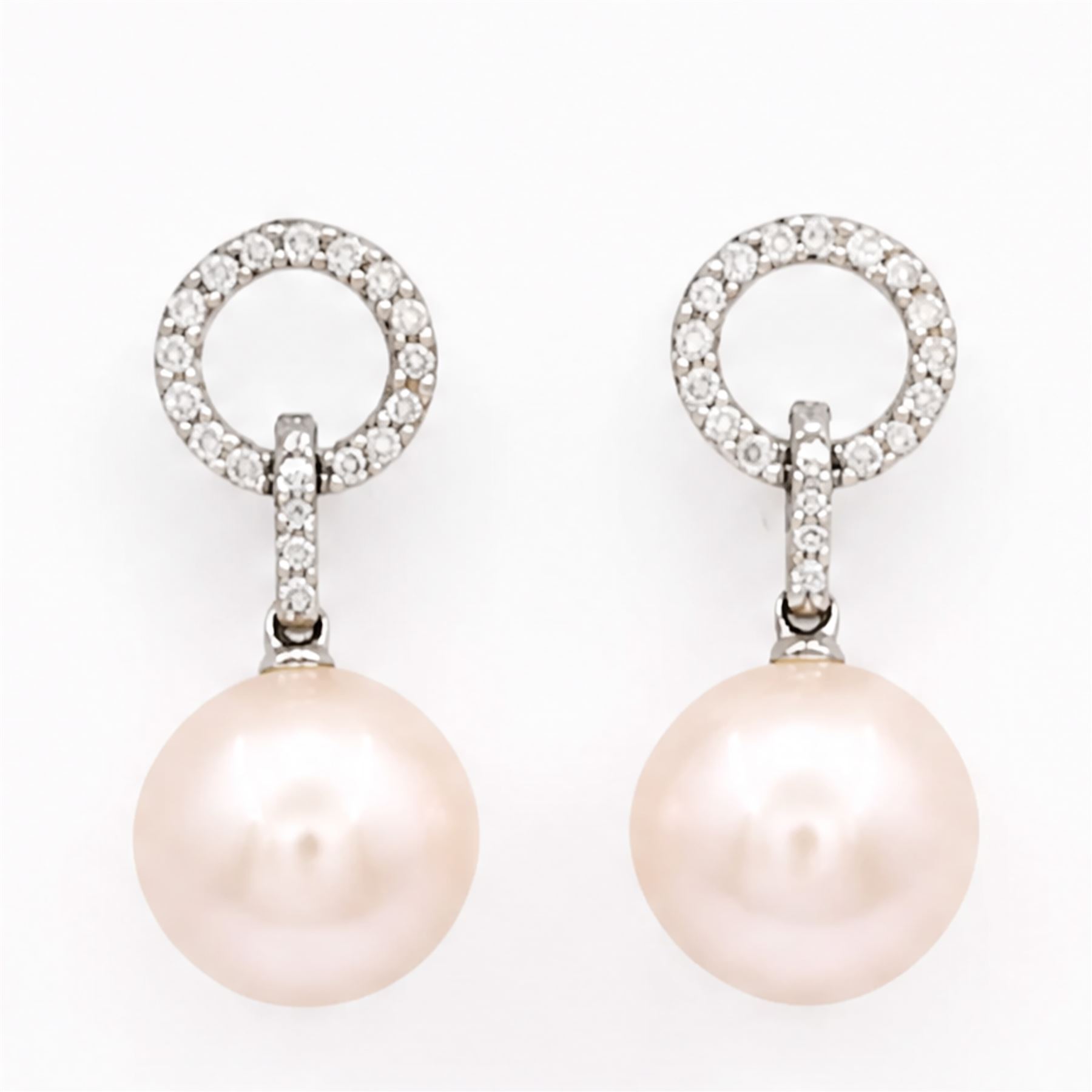 Pair of 18ct white gold pearl and diamond pedant earrings, each stud set with a halo of round cut diamonds, suspending further diamonds and a single peach / pink pearl, stamped 750