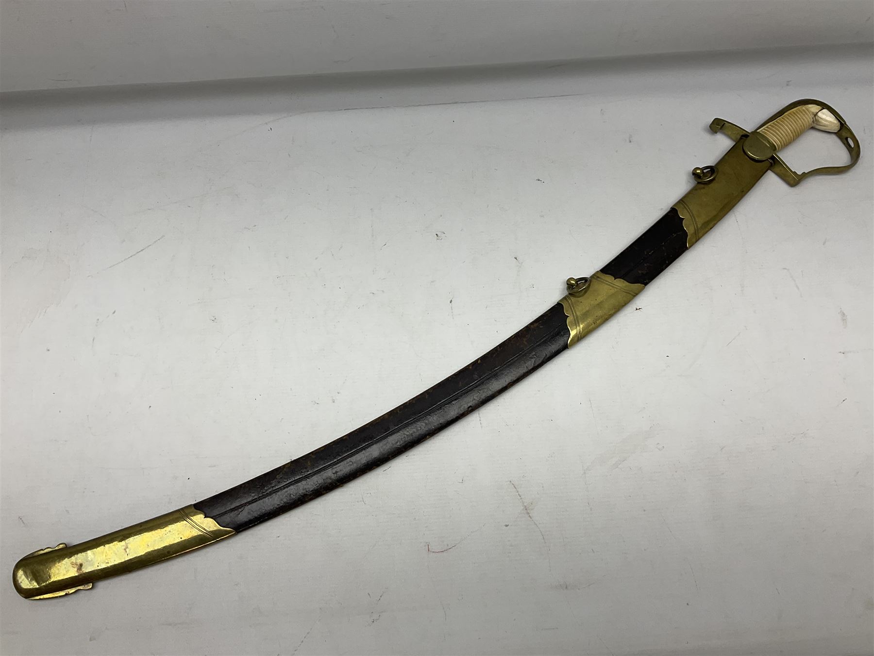 British pattern 1796 Light Cavalry Officer's sword, the 83.5cm curving steel blade marked 'W. Parker London' and 'Warranted' verso, brass stirrup hilt with half-round langets, knucklebow and backstrap with ribbed ivory grip; in brass mounted leather covered scabbard with two suspension rings L97cm overall. This item has been registered for sale under Section 10 of the APHA Ivory Act 