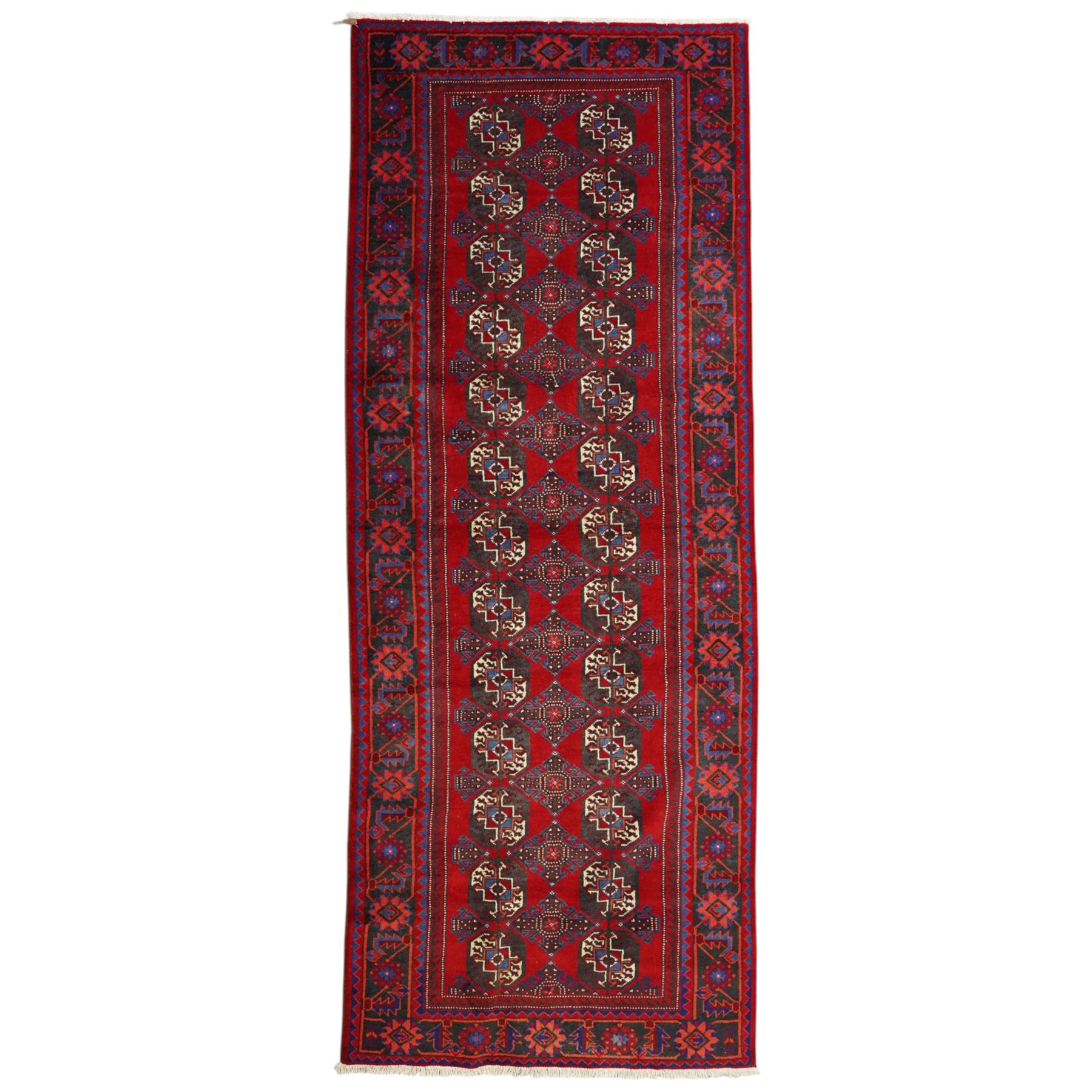 North East Persian Balochi hand-knotted runner, crimson field decorated with three vertical columns of repeating octagonal guls, each enclosing angular geometric motifs in deep indigo, ivory, and soft brown tones, guls linked by stepped diamond and cruciform devices, main border of stylized geometric floral motifs and angular vines, flanked by multiple guard borders, with cotton fringe ends 