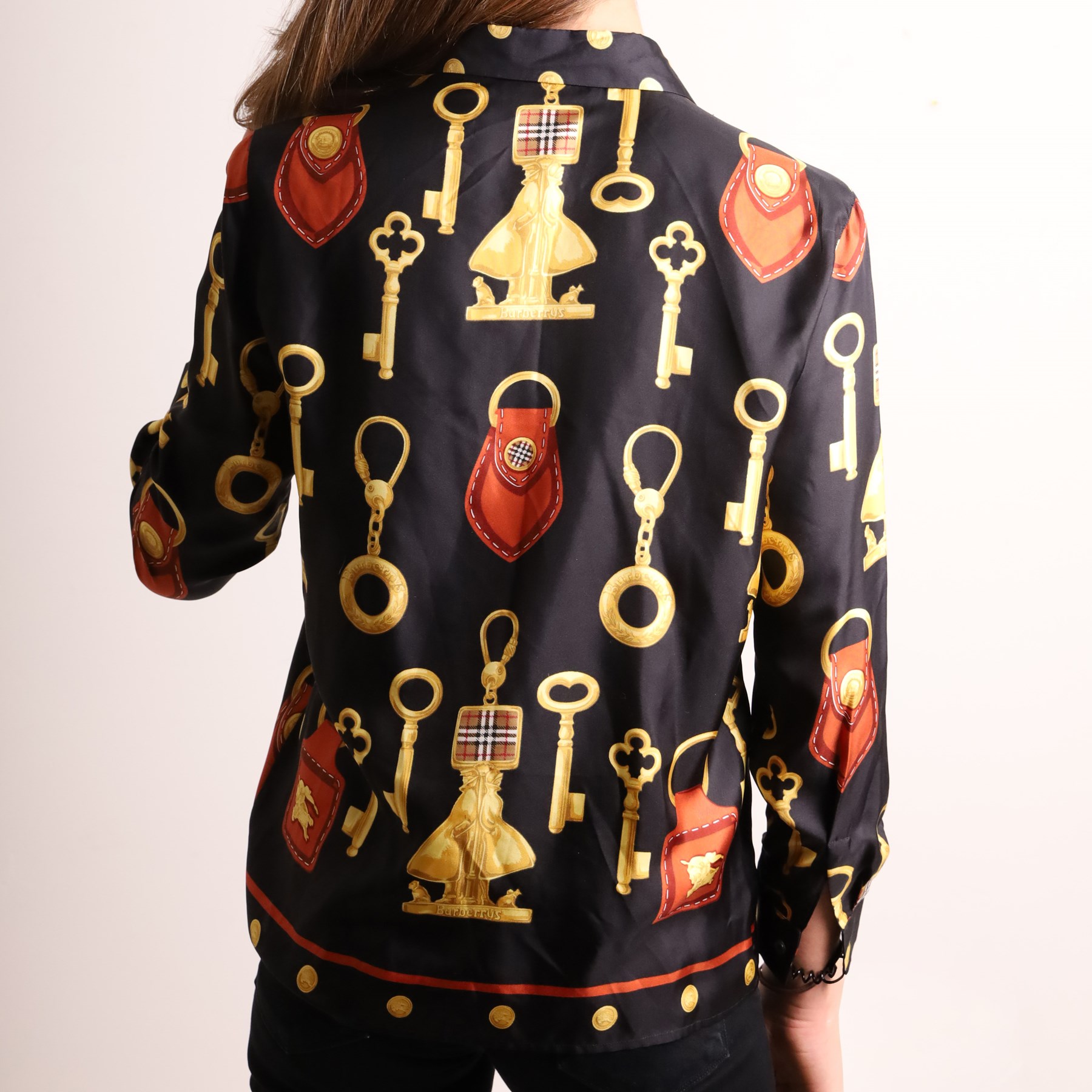 Burberrys – navy wool blazer and silk shirt, the blazer made in England, with gilt Burberry buttons, embroidered monogrammed breast pocket, black lining with Burberry motif and branded sleeve label, size S/M; the blouse in black 100% silk with all-over novelty print of keys, padlocks, coins and Burberry check motifs in yellow, orange and red, size S, made in Italy (2)