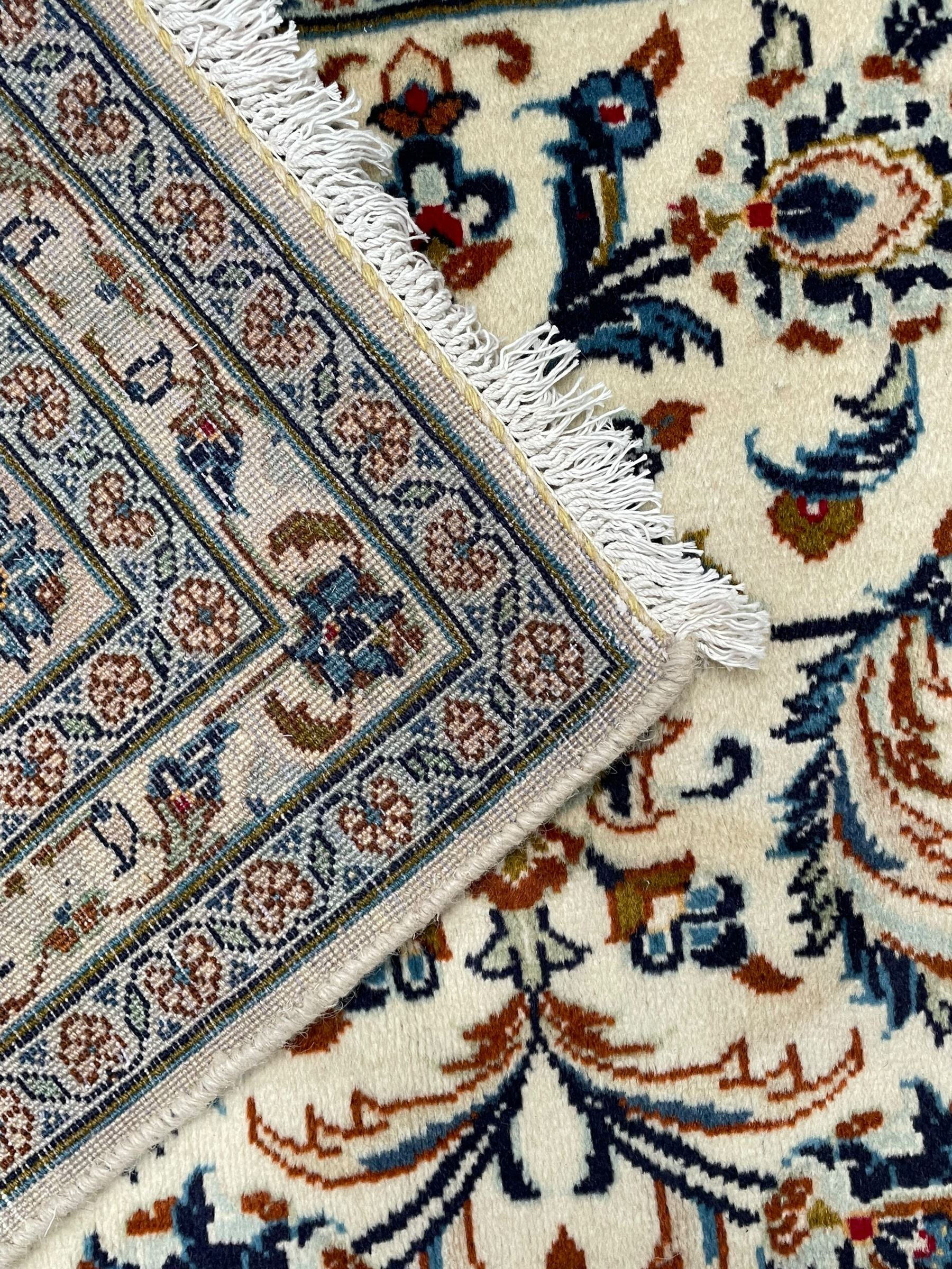 Persian Kashan ivory ground rug, decorated with curled leafy branches and palmettes, the border with scrolling design decorated with further palmettes, within floral pattern guard stripes