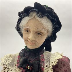 Anna Meszaros Hungary - hand made needlework finely detailed figurine of a pensive old lady seated on a stool wearing a lace trimmed long black and maroon dress and hat, clutching a lace bag H32cm Auctioneer's Note: Anna Meszaros came to England from her native Hungary in 1959 to marry an English businessman she met while demonstrating her art at the 1958 Brussels Exhibition. Shortly before she left for England she was awarded the title of Folk Artist Master by the Hungarian Government. Anna was a gifted painter of mainly portraits and sculptress before starting to make her figurines which are completely hand made and unique, each with a character and expression of its own. The hands, feet and face are sculptured by layering the material and pulling the features into place with needle and thread. She died in Hull in 1998.