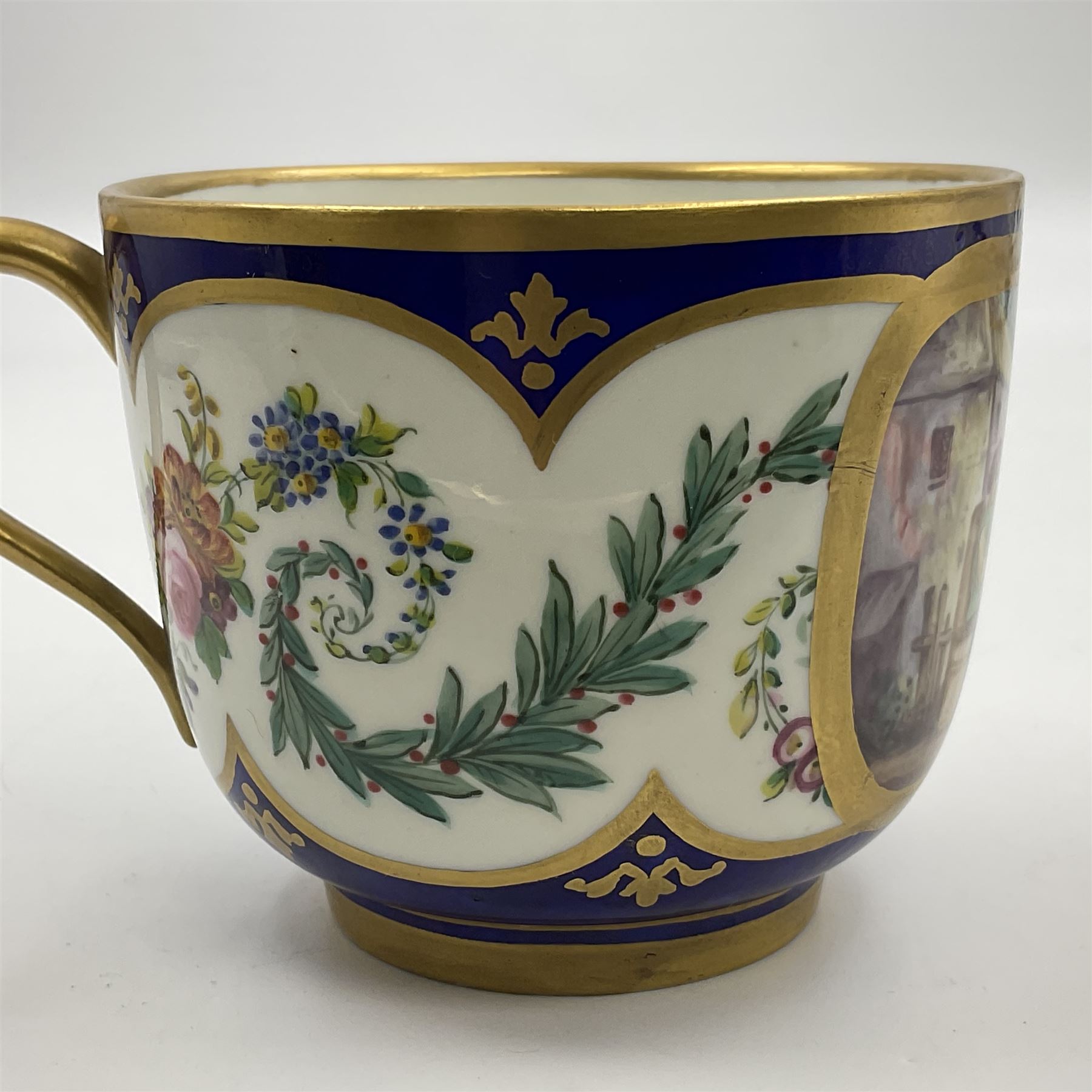 19th Sèvres style porcelain cup and saucer, the cup painted with a figural scene, against a scalloped border of scrolling floral swags on a blue ground, together with a Sèvres soft paste porcelain coffee can and saucer, painted with panels of exotic birds, roses and a border of cornflowers, LL monogram enclosing date letters H above painters mark, coffee can H6.5cm, saucer D13.5cm (2)