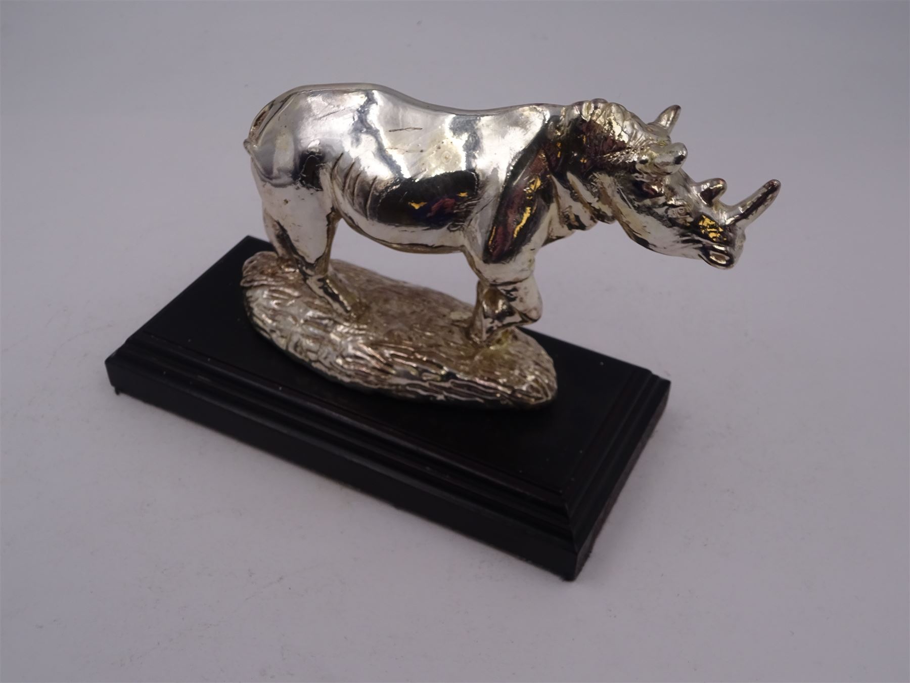 Filled silver model of a rhinoceros by Afrisilver, upon lacquered wooden base, H11.5cm